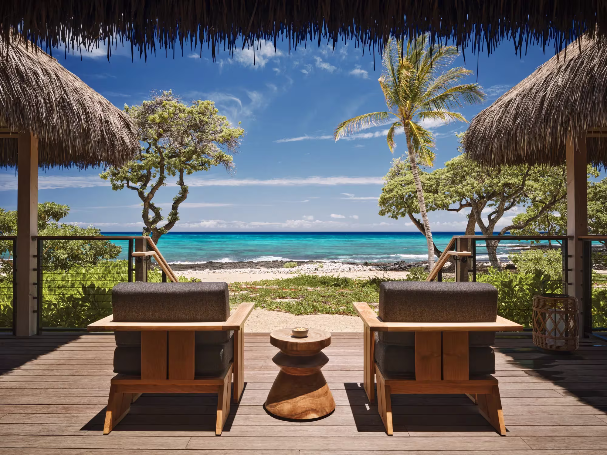 Lanai eines Beachfront Hale im Rosewood Kona Village mit Liegestühlen unter Palmen direkt am Sand