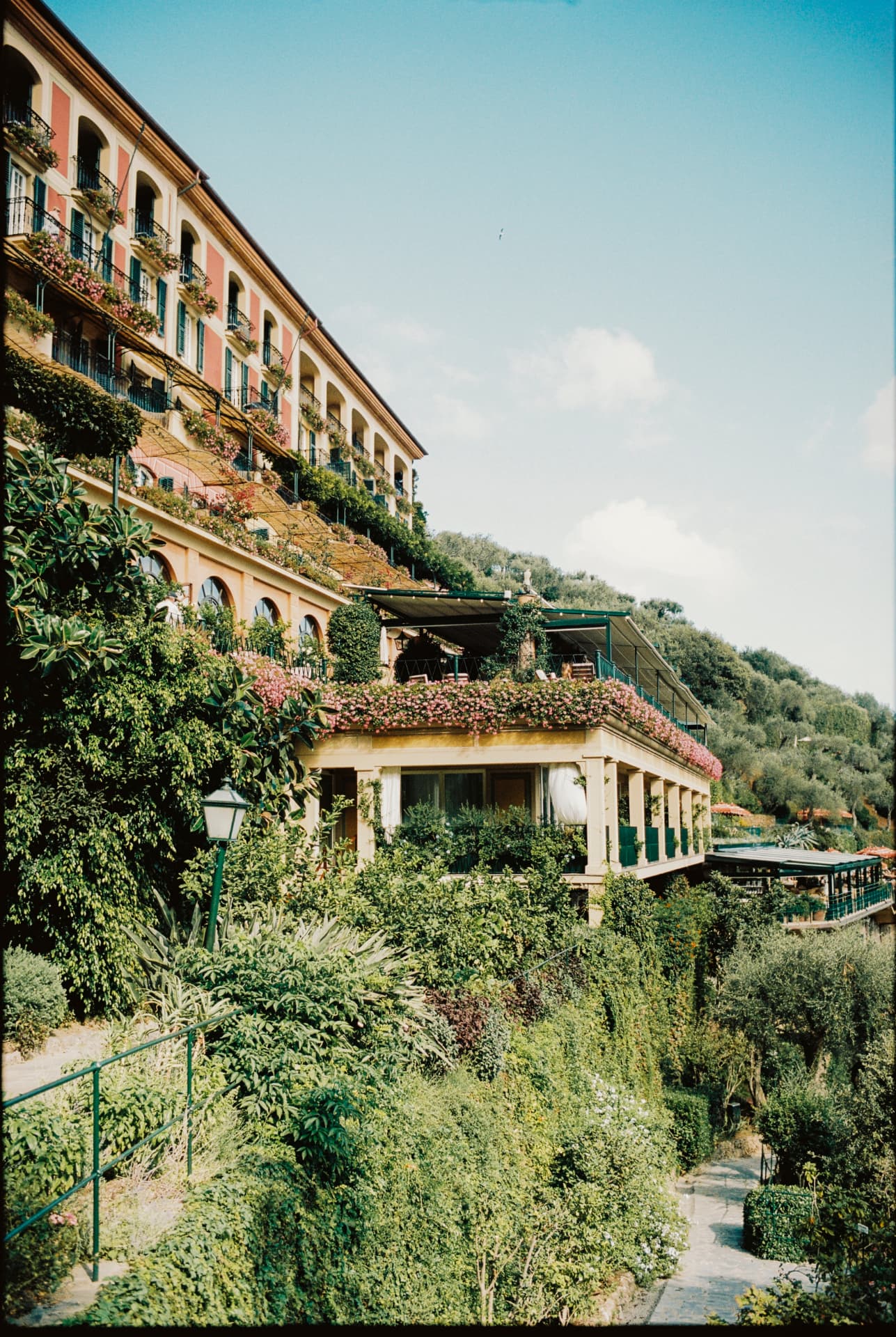 Die Terrassen des Hauses im Hang, überwachsen von Bougainvillea und Oleander, darunter die Pergola des Restaurants