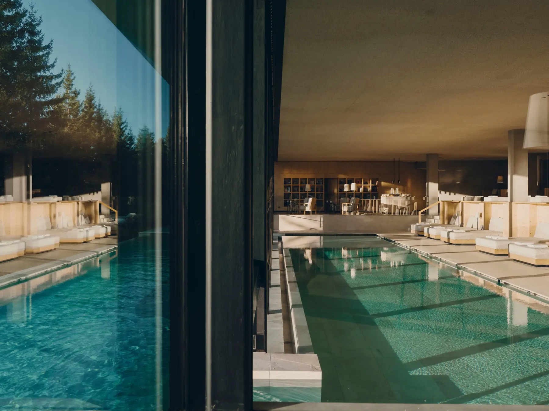 Innenpool in Naturstein mit Liegen aus Fichtenholz und Blick in den Wald