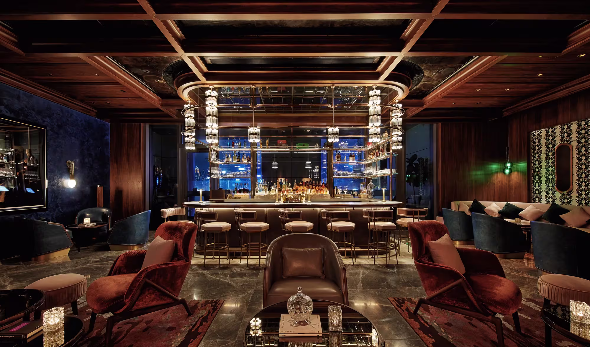 Die Bar DarkSide im Rosewood Hong Kong mit dunkler Holzvertäfelung, Bronzeleisten an der Decke, ledernen Sesseln und einer beleuchteten Spirituosenwand