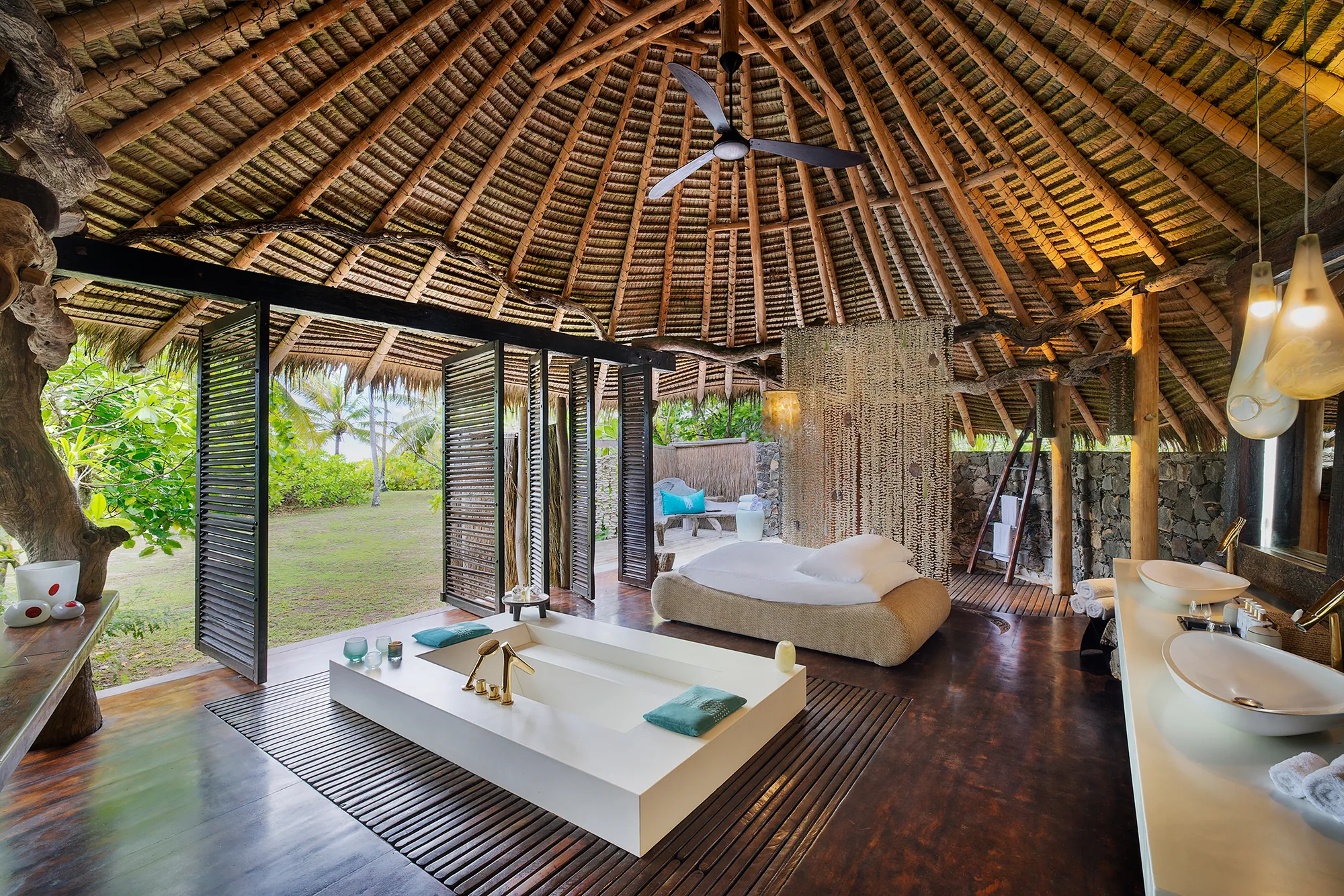 Badezimmer einer Villa mit freistehender Wanne und Blick in den Garten