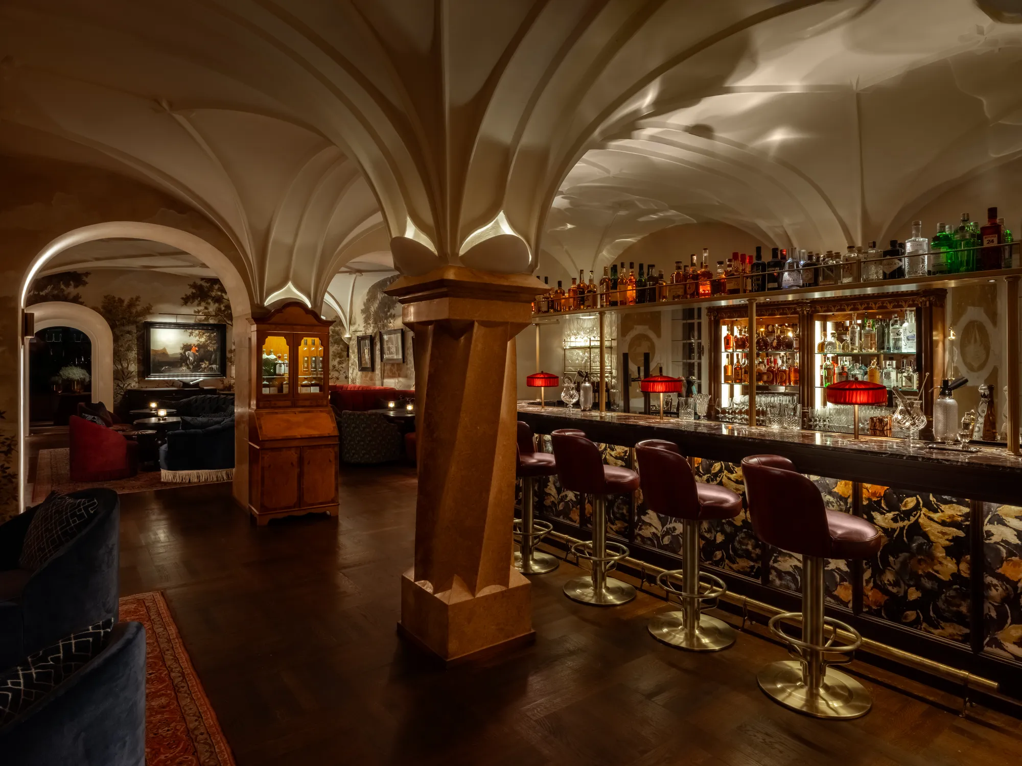 Die Schloss Bar mit spätgotischem Gewölbe, langem Tresen, roten Lampenschirmen und dunklen Ledersesseln