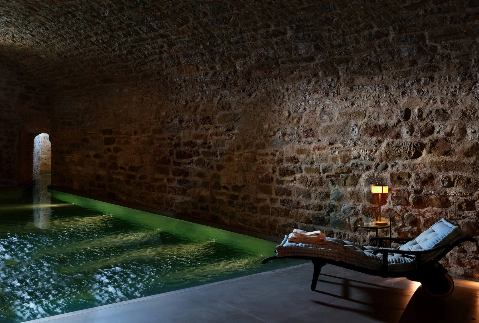 Schmaler Pool im Gewölbekeller mit alten Steinwänden und warmem Licht