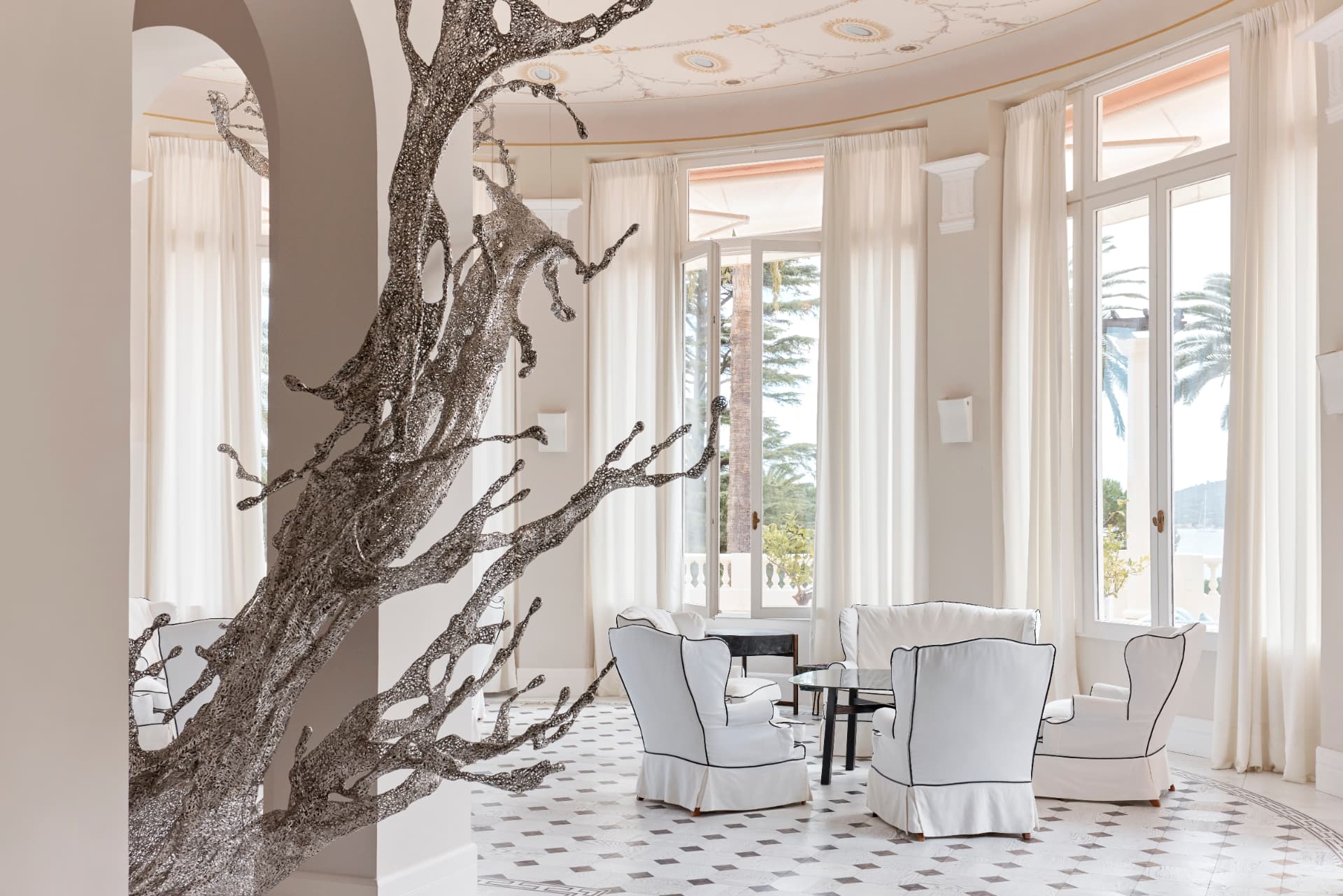 Rotunde der Lobby mit filigraner Baumskulptur und weißen Sesseln
