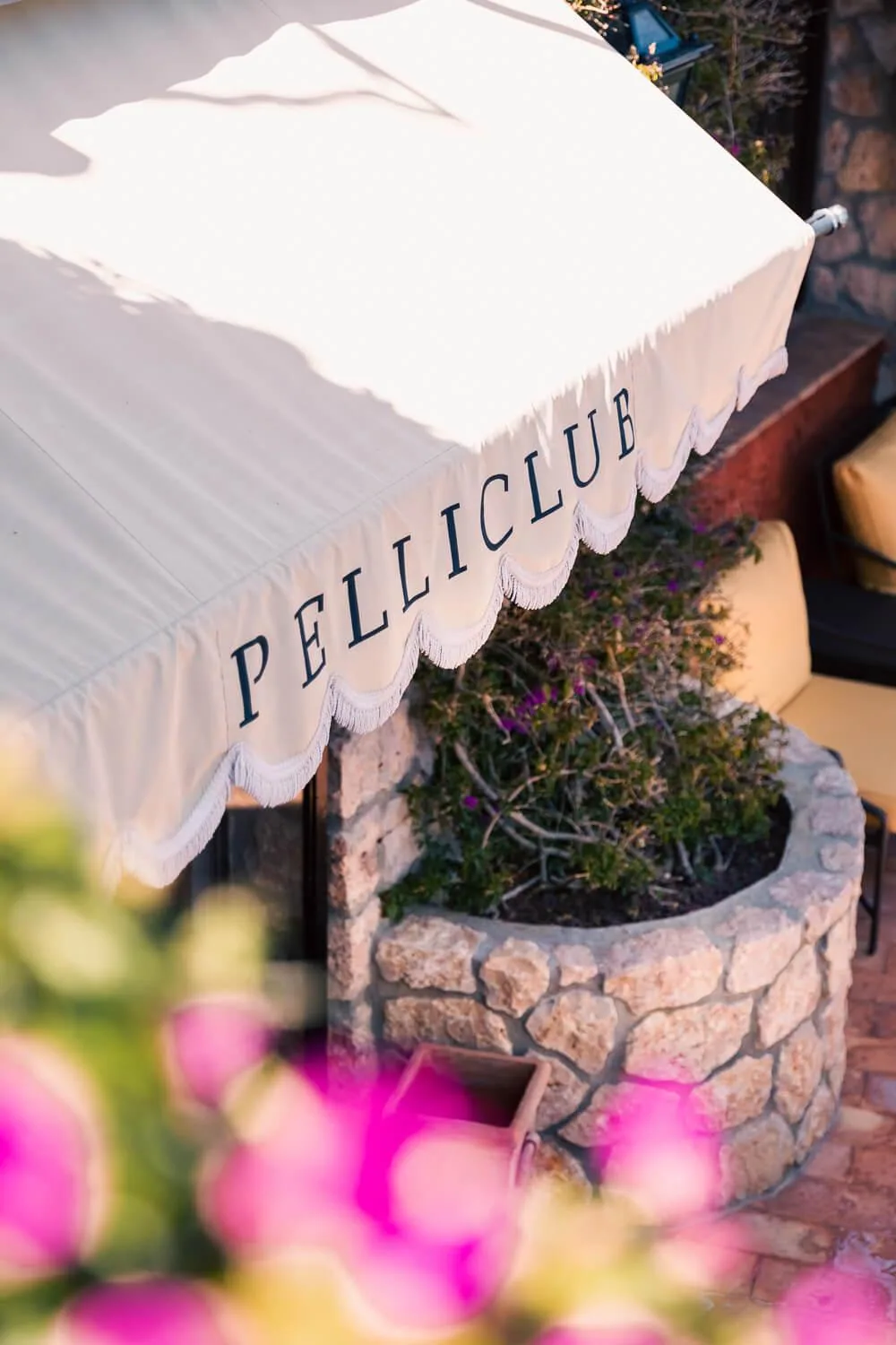 Markise des Pelliclub über der Steinmauer mit Bougainvillea