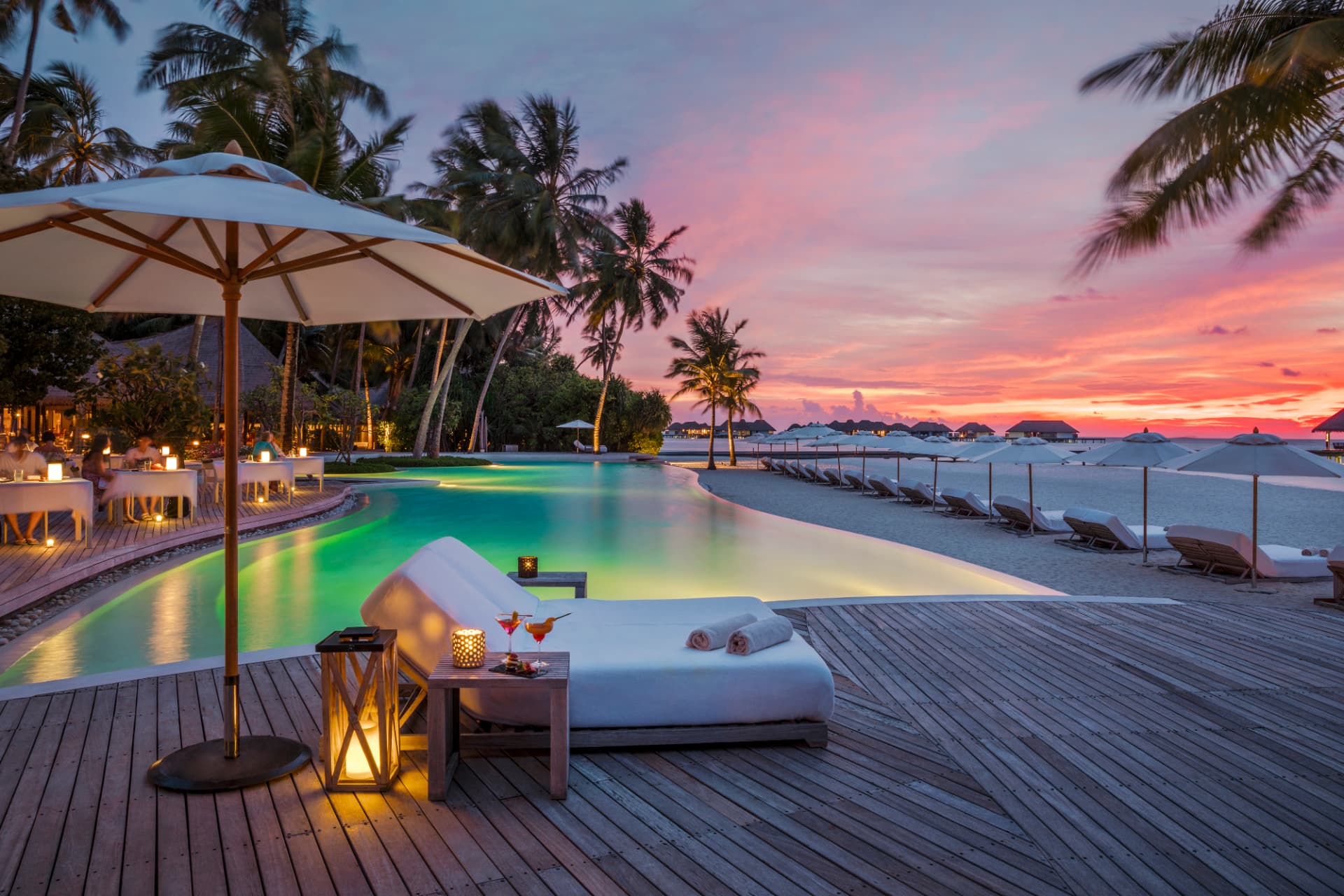 Pooldeck mit Liegen und Laternen im Abendrot