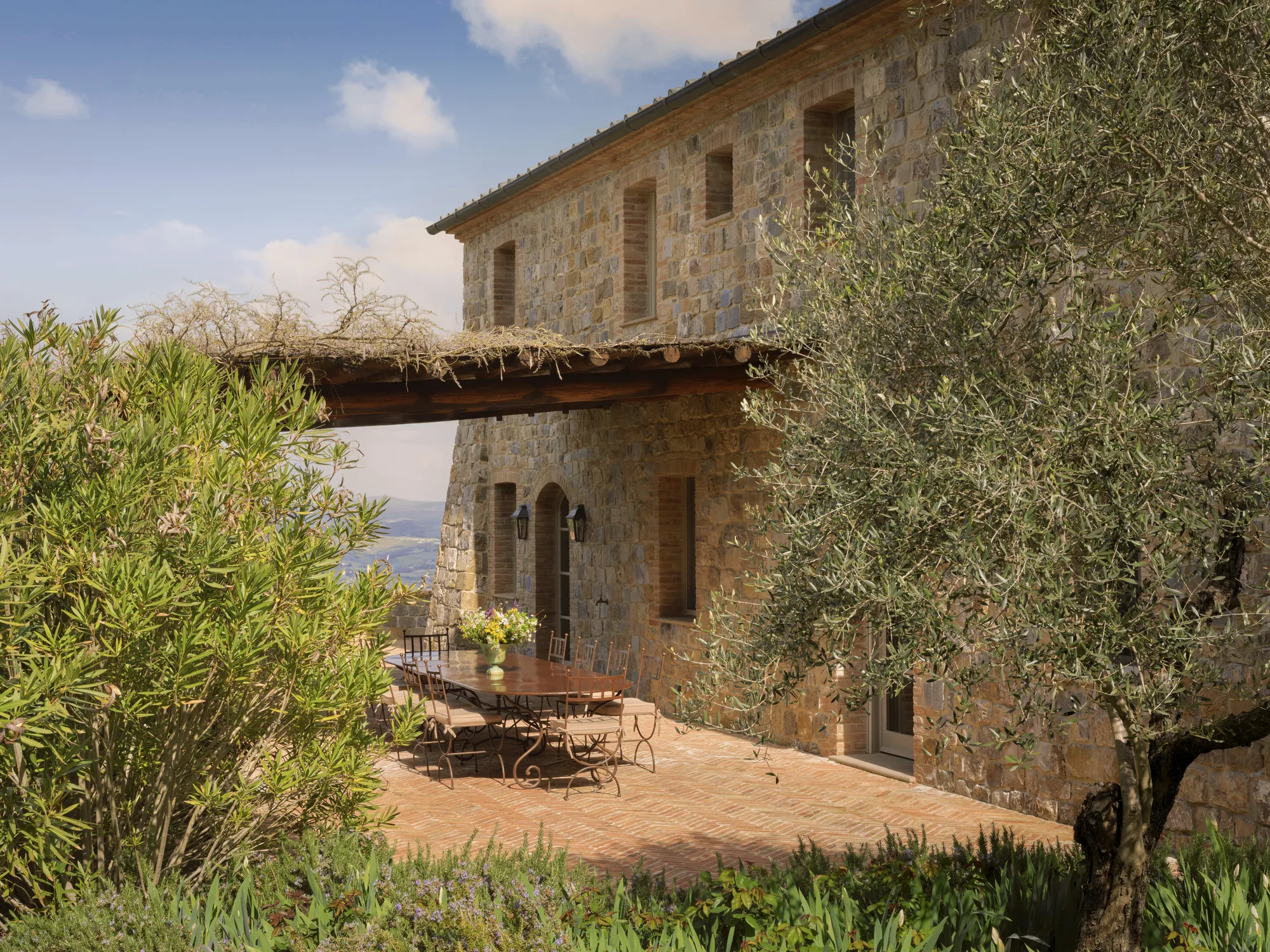 Terrasse der Villa Agresto: langer Esstisch unter der Pergola, Olivenbäume und Blick über die Hügel