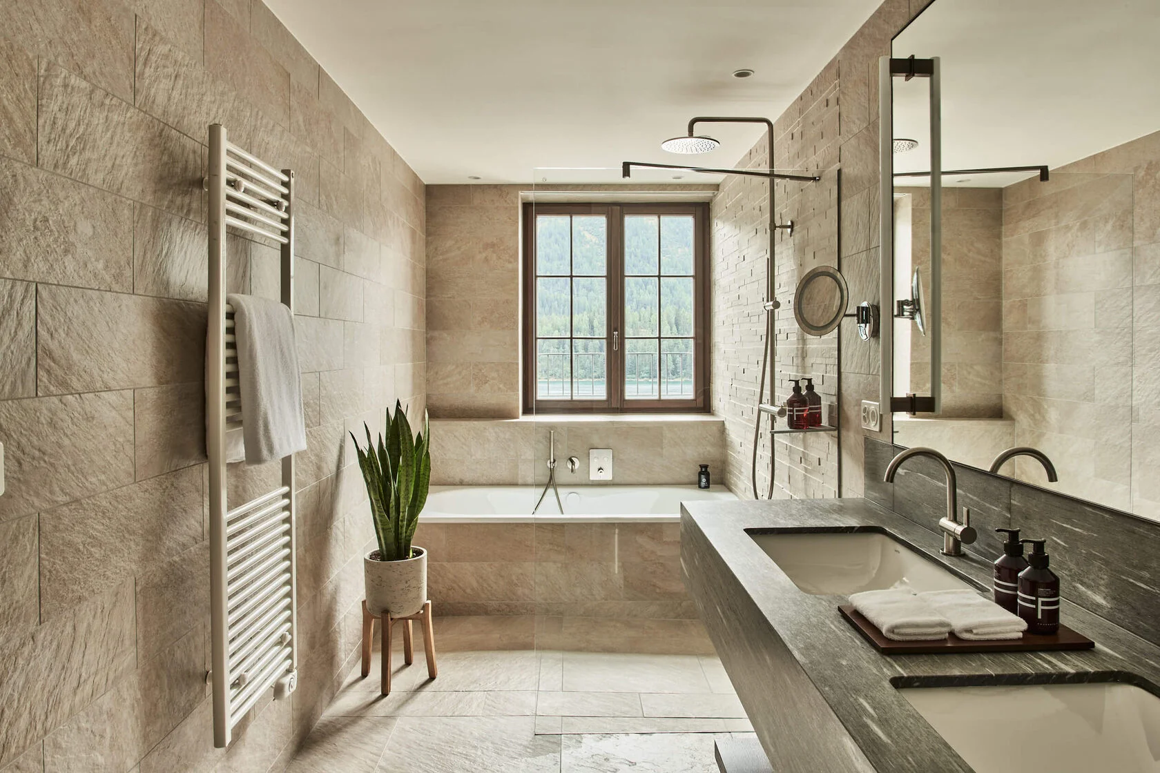 Bad in hellem Naturstein mit Wanne am Fenster