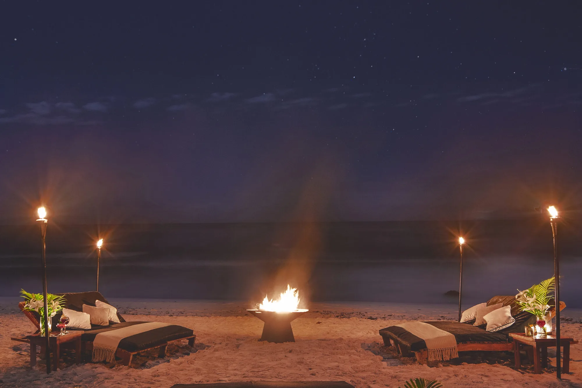 Lagerfeuer und Liegen am leeren Strand in der Abenddämmerung