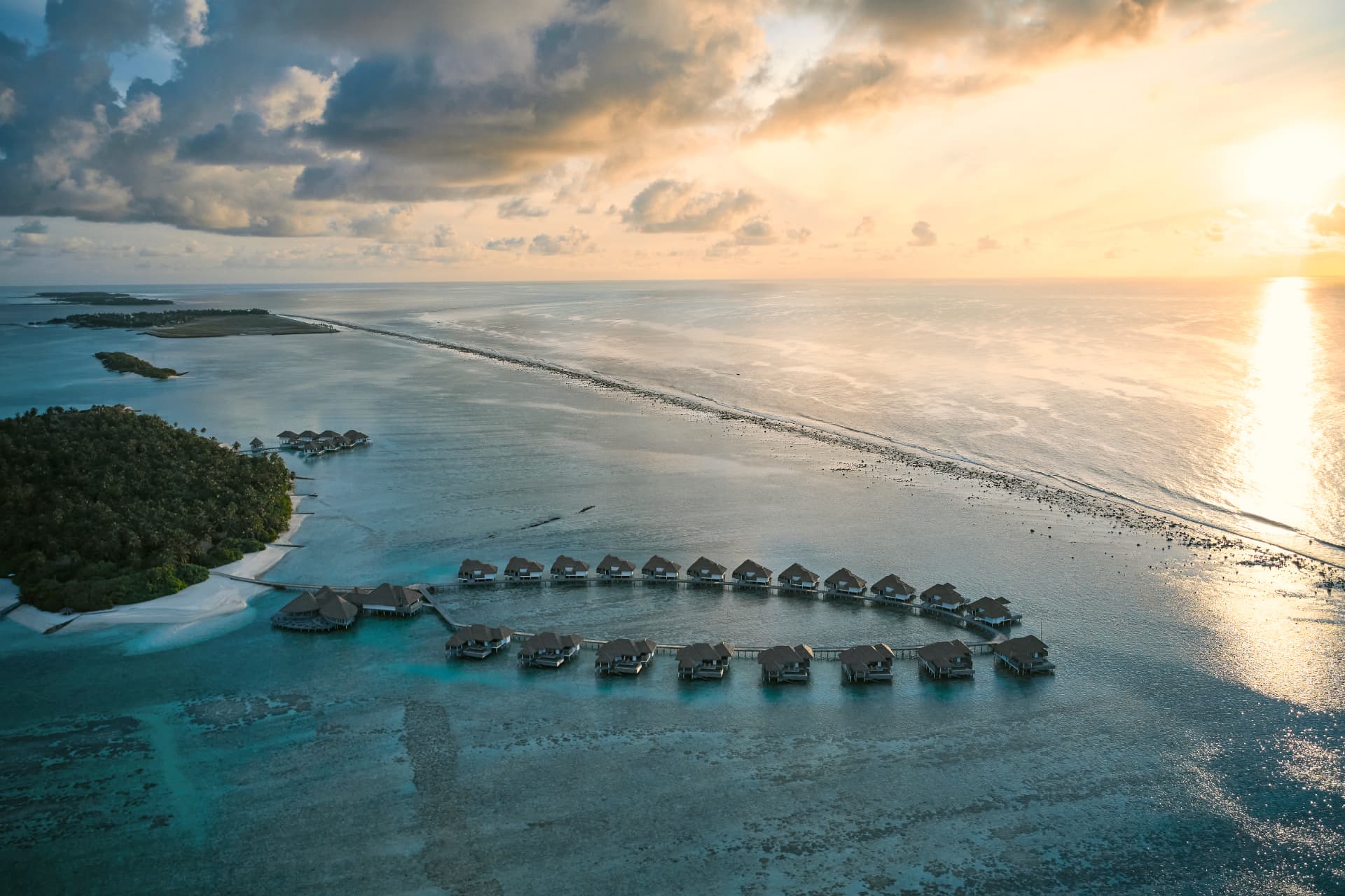 COMO Maalifushi aus der Luft: Reihe von Wasservillen im Thaa-Atoll bei Sonnenuntergang