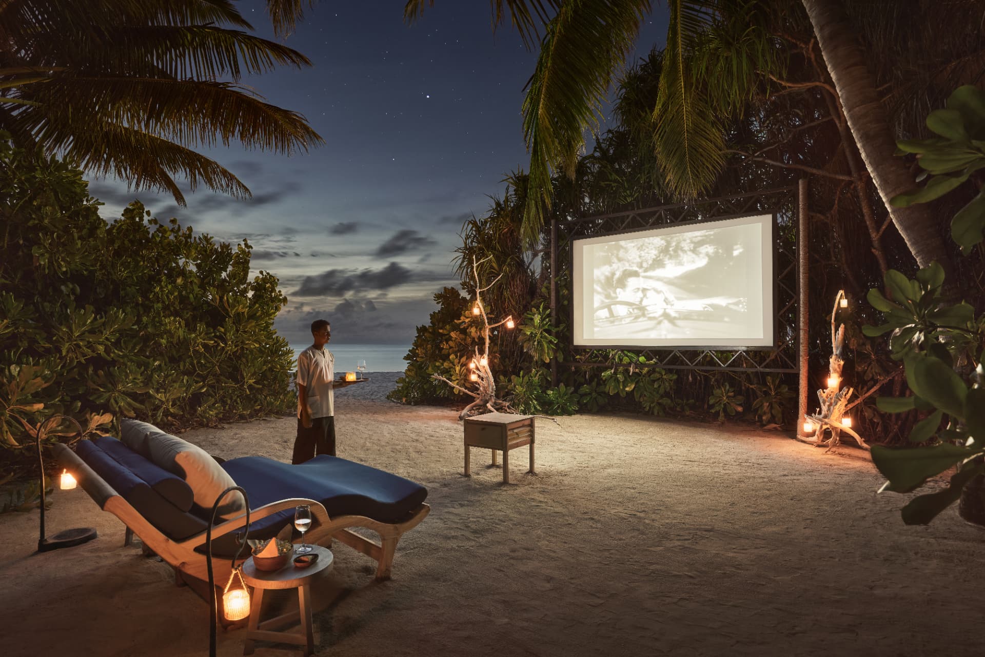 Kino im Freien zwischen Palmen mit Laternen im Sand