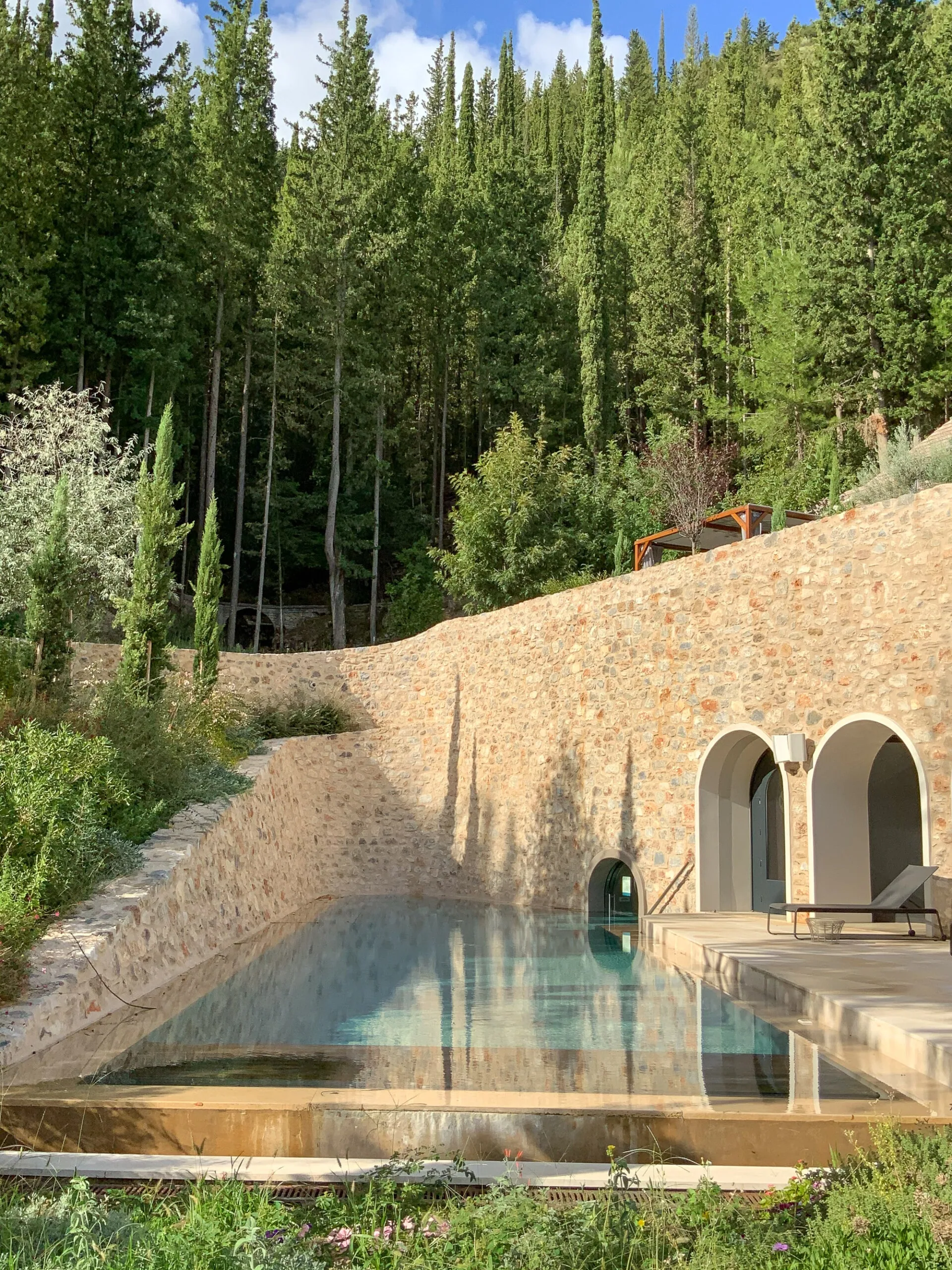 Pool zwischen Zypressen mit den Bögen des Hauses dahinter