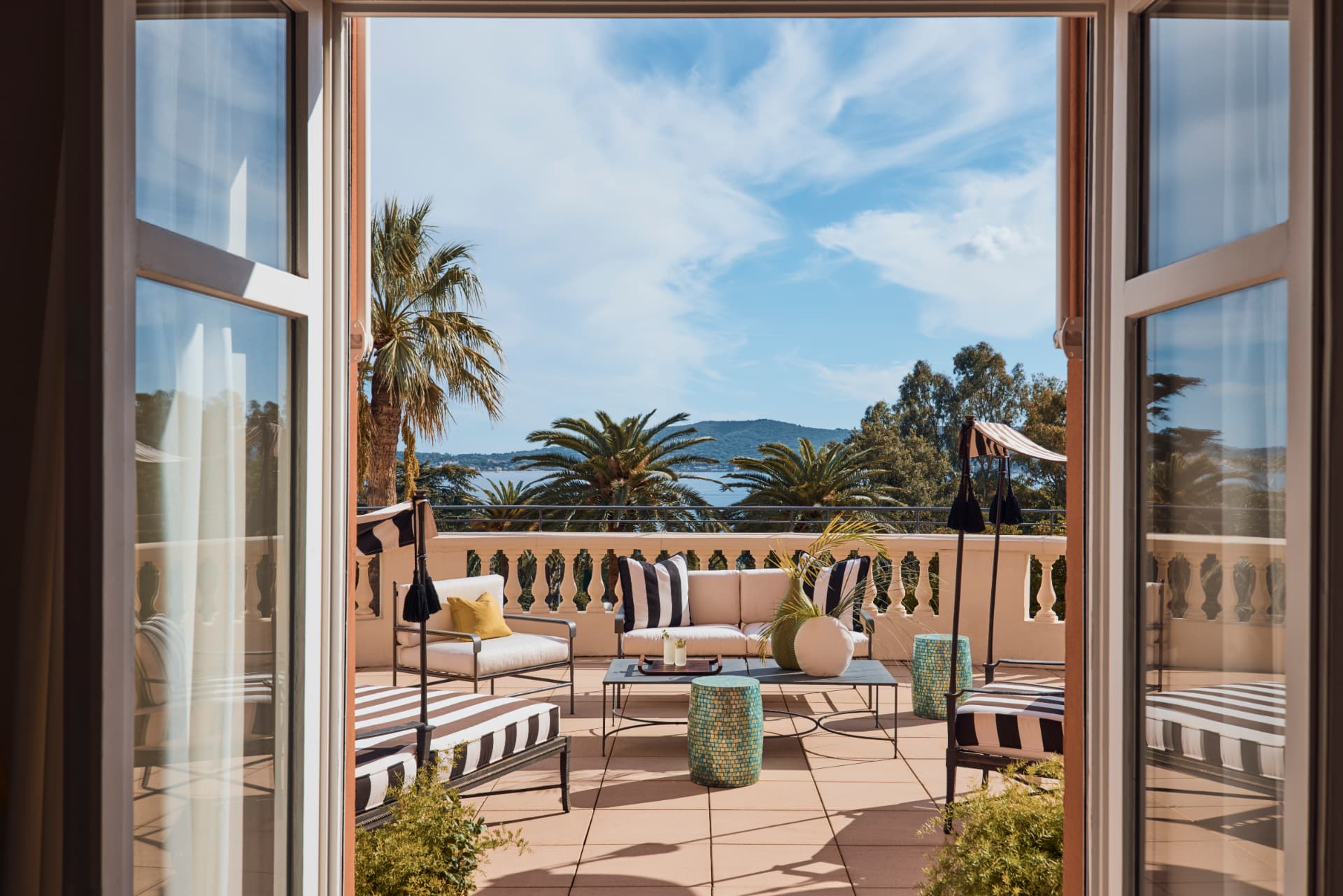 Terrasse der Two Bedroom Suite mit gestreiften Liegen über Palmen und Meer