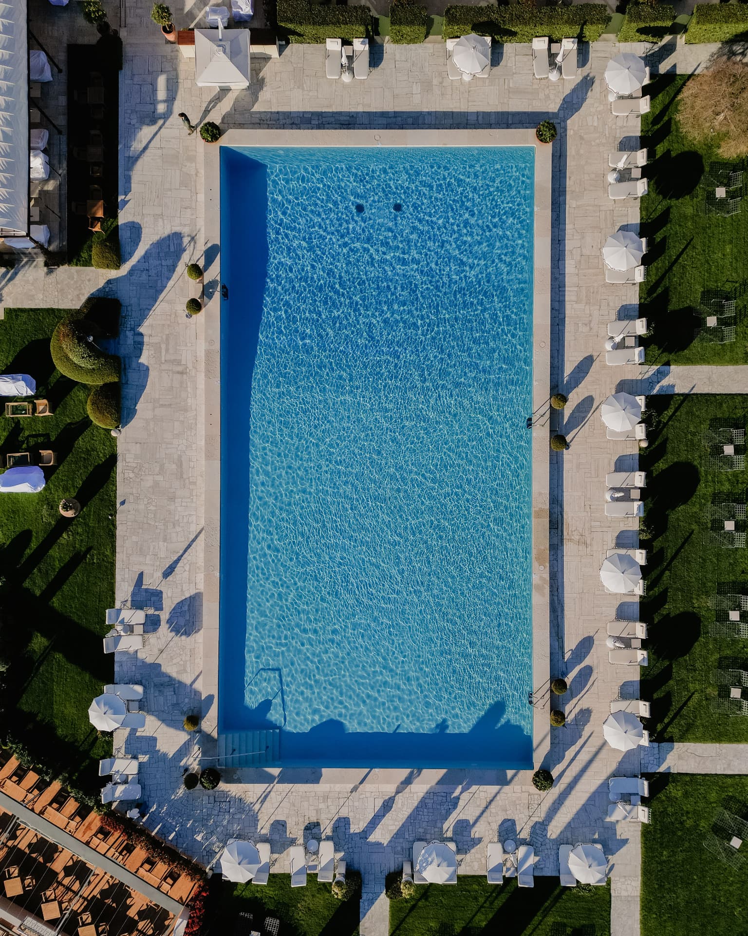 Der olympische Pool des Hotel Cipriani von oben, umgeben von Liegen, Schirmen und Rasenflächen