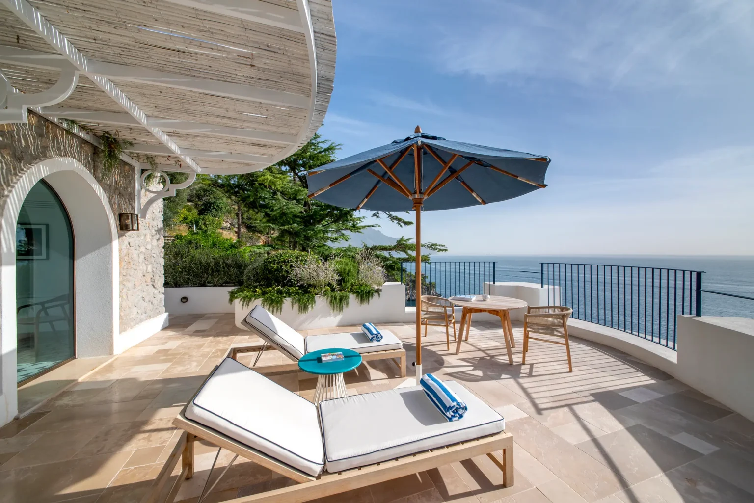 Terrasse einer Deluxe-Suite mit Liegen hoch über dem Meer