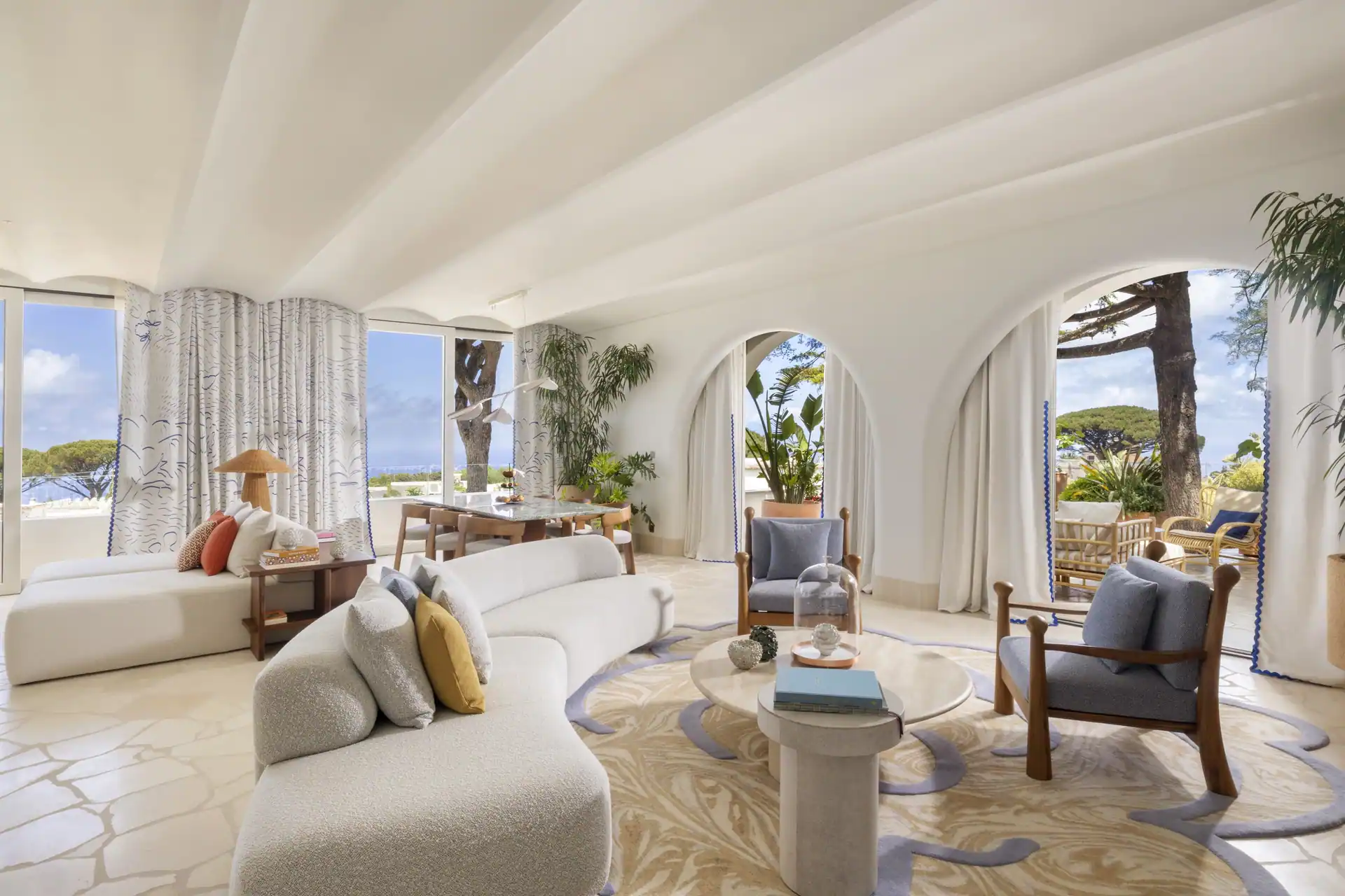 Wohnraum einer Suite mit gewölbter weißer Decke, hellen Sofas und Blick in den Garten