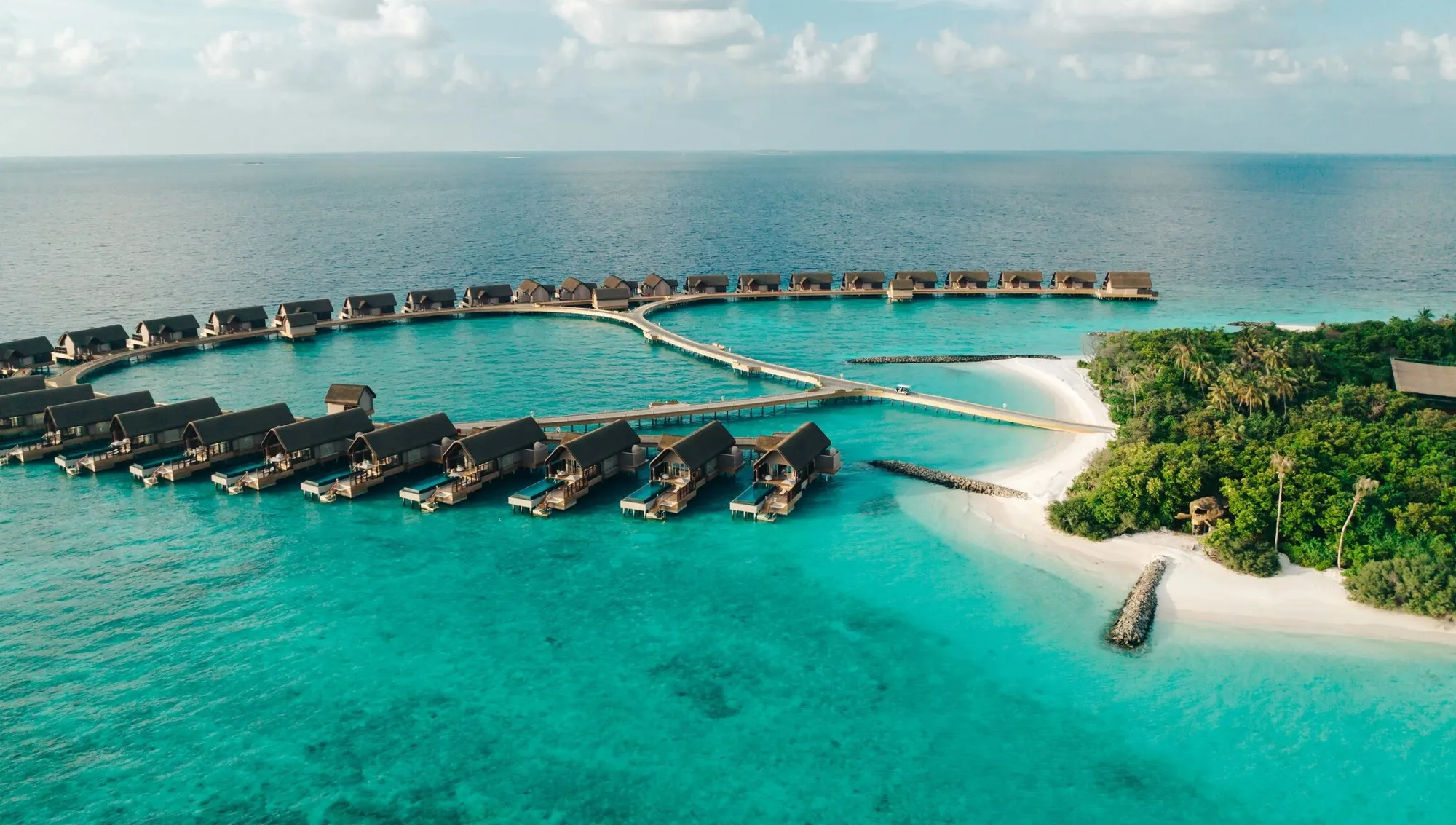 Luftaufnahme der Überwasser-Villen von JOALI Maldives über dem Riff
