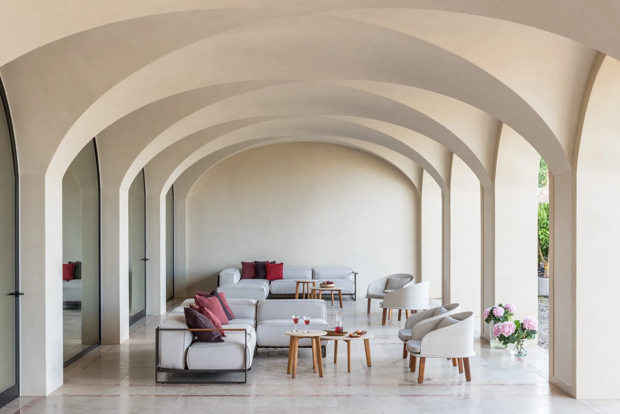 Gewölbter Aufenthaltsraum mit hellen Sofas und Bogenfenstern