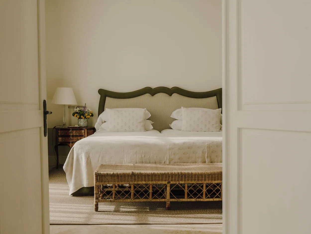 Schlafzimmer in der Finca Cortesin mit hellen Wänden, Leinenbett und Korbmöbeln