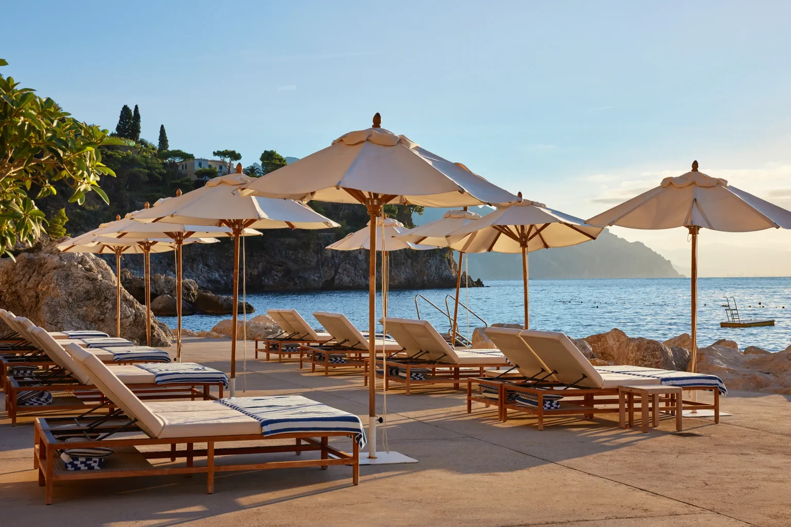 Beach Club des Borgo Santandrea mit Schirmen und Liegen am Kiesstrand