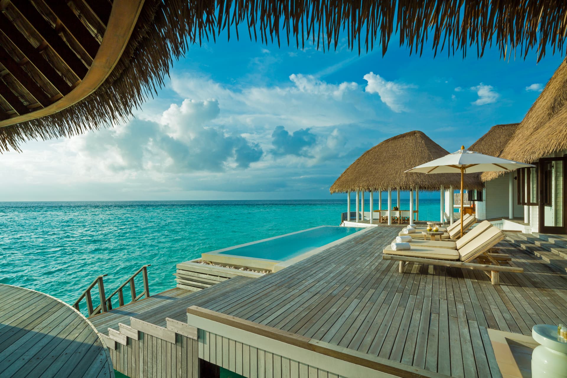 Deck der COMO Villa mit Infinity-Pool und Liegen über dem Riff