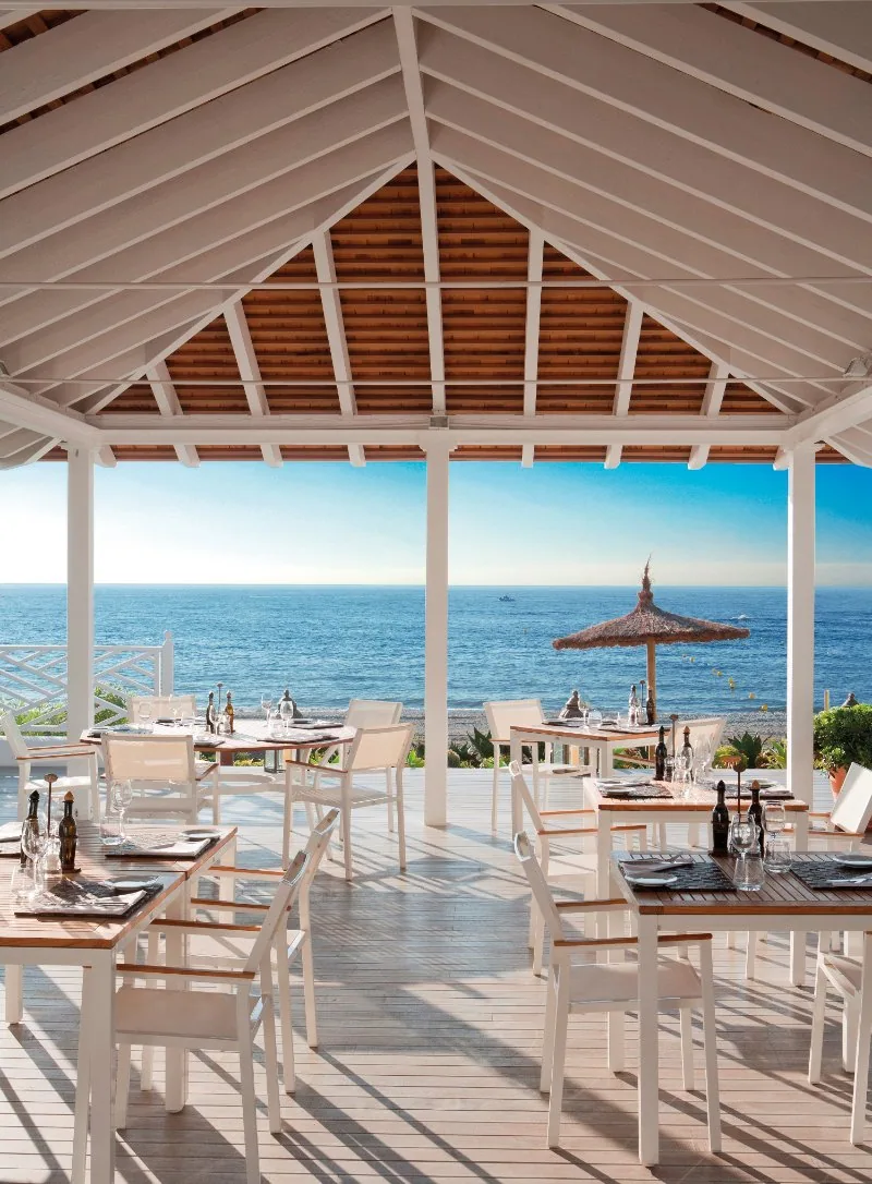 Beach Club der Finca Cortesin mit weißen Stühlen unter offenem Dach am Meer