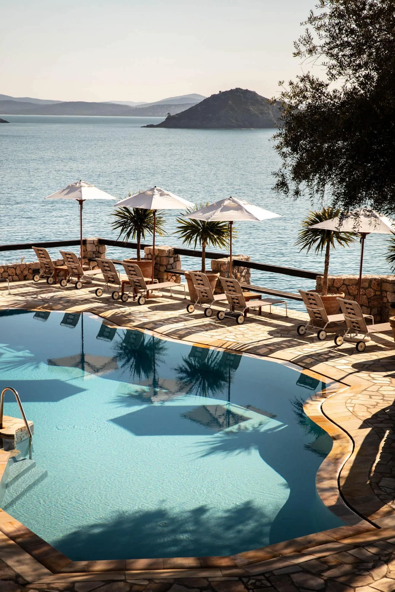 Pool des Il Pellicano über dem Meer, umgeben von Sonnenschirmen und Pinien