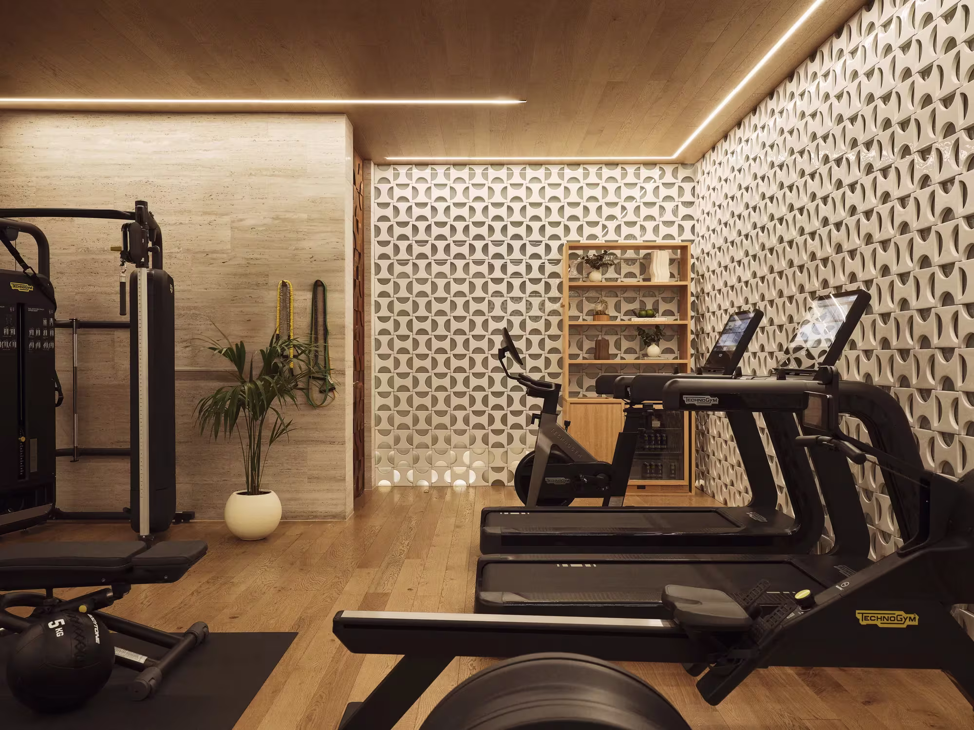 Fitnessbereich des Rosewood Villa Magna mit Geräten, Holzboden und gemustertem Wandpaneel