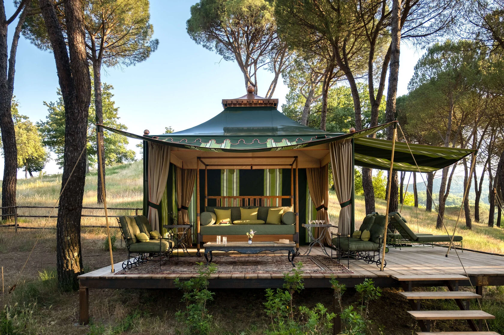Grüner Gartenpavillon auf einer Holzterrasse zwischen Pinien
