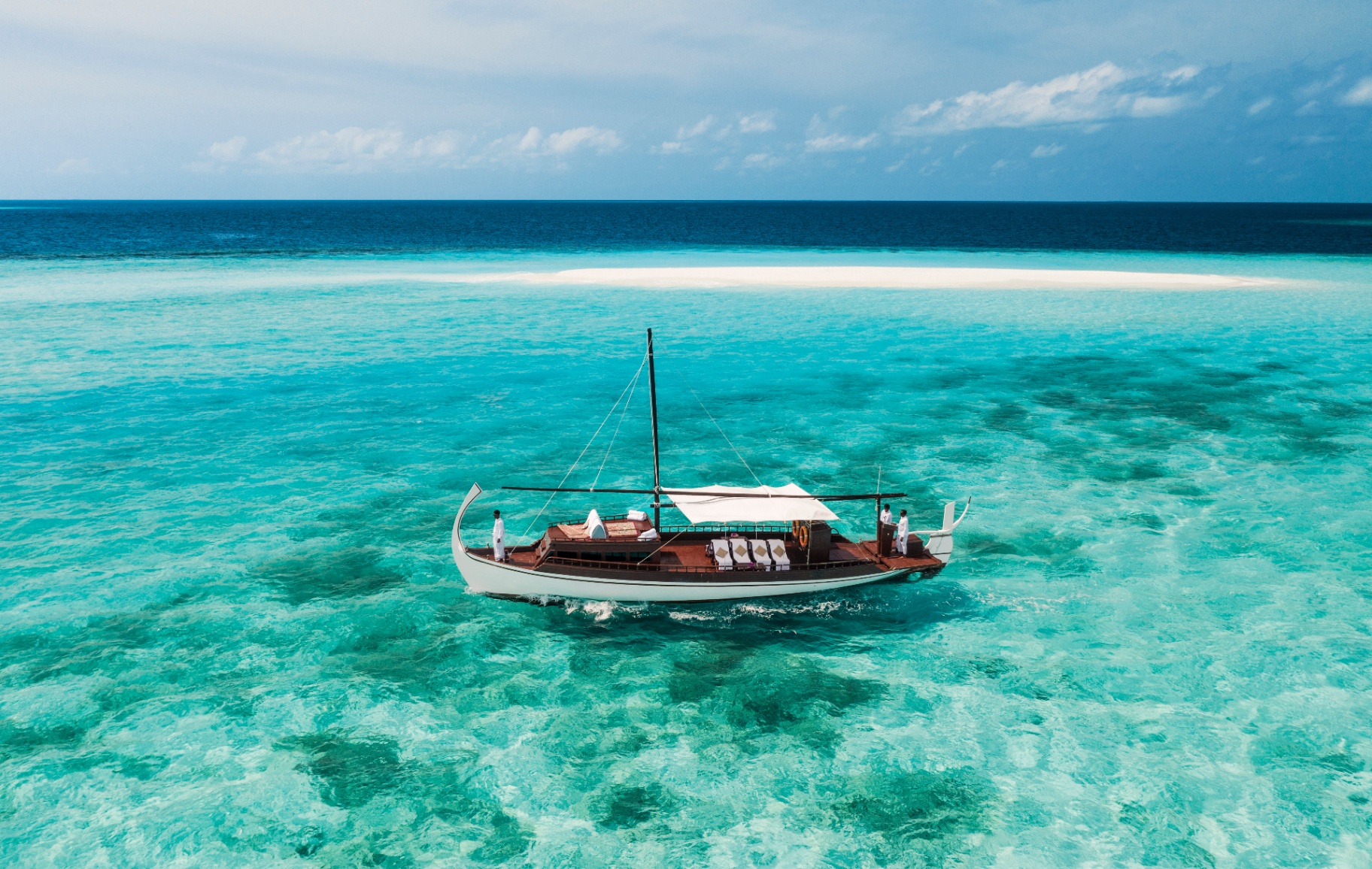 Traditionelle Dhoni auf türkisfarbenem Wasser vor einer leeren weißen Sandbank