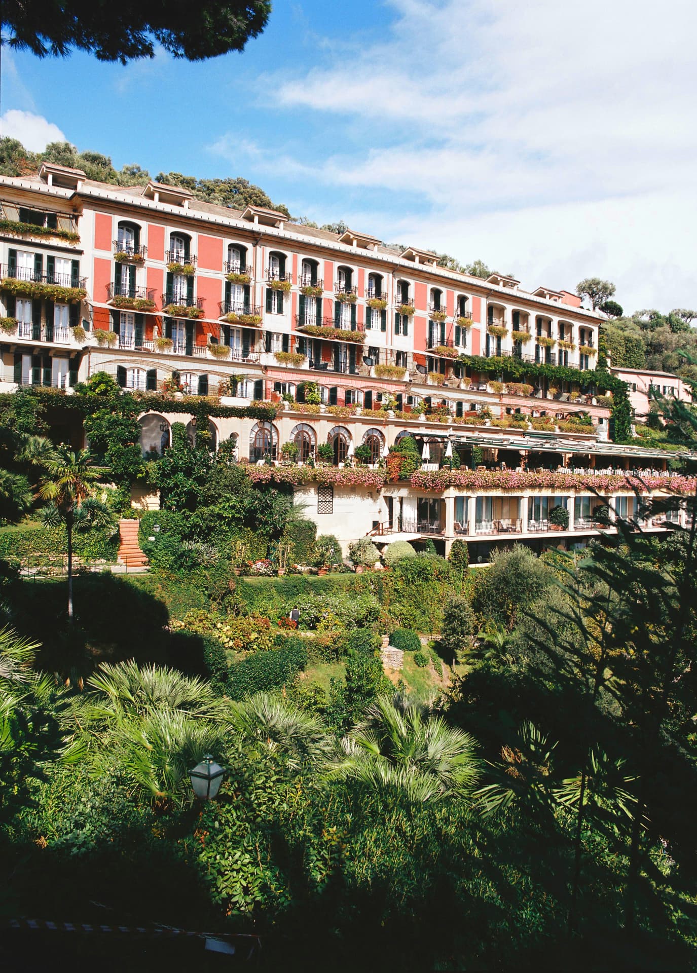 Die rosa-weiße Fassade des Splendido im Pinienhang über Portofino, davor die terrassierten Gärten mit Palmen und Blumenkästen