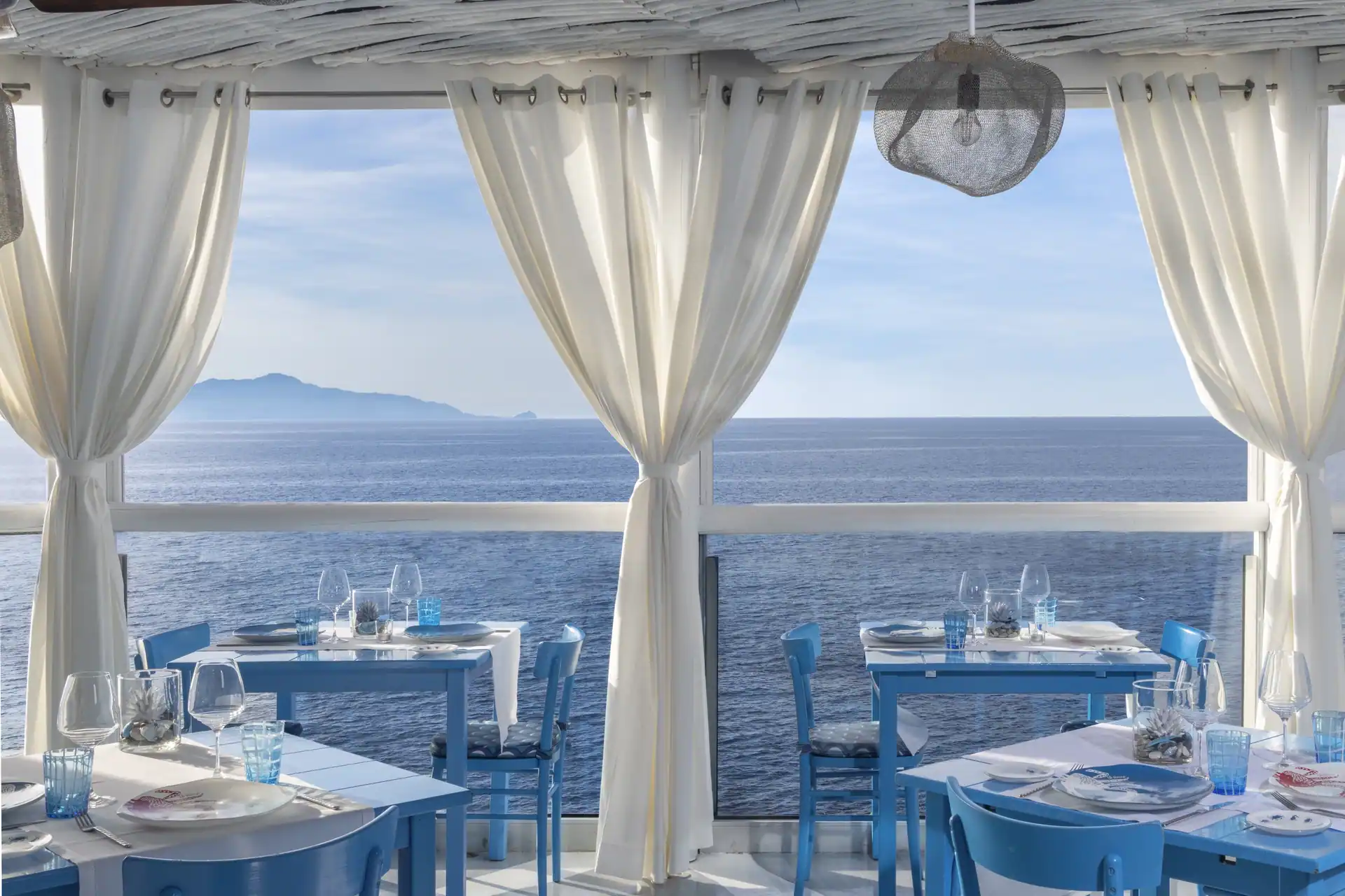 Blau-weiß gedeckte Tische des Il Riccio mit offenem Blick auf das Meer
