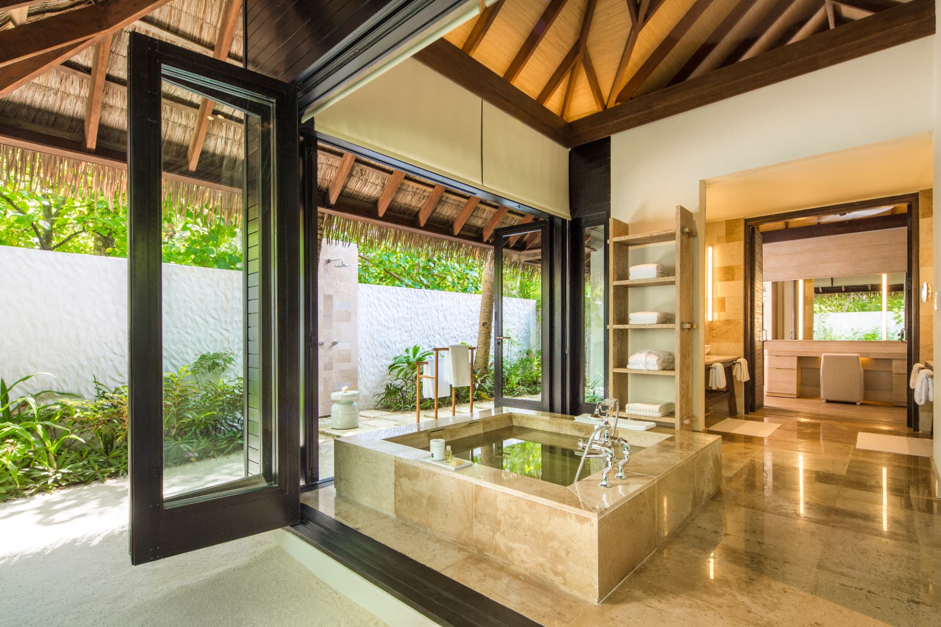 Badezimmer der Beach Suite mit eingelassener Steinwanne und Zugang zur Außendusche
