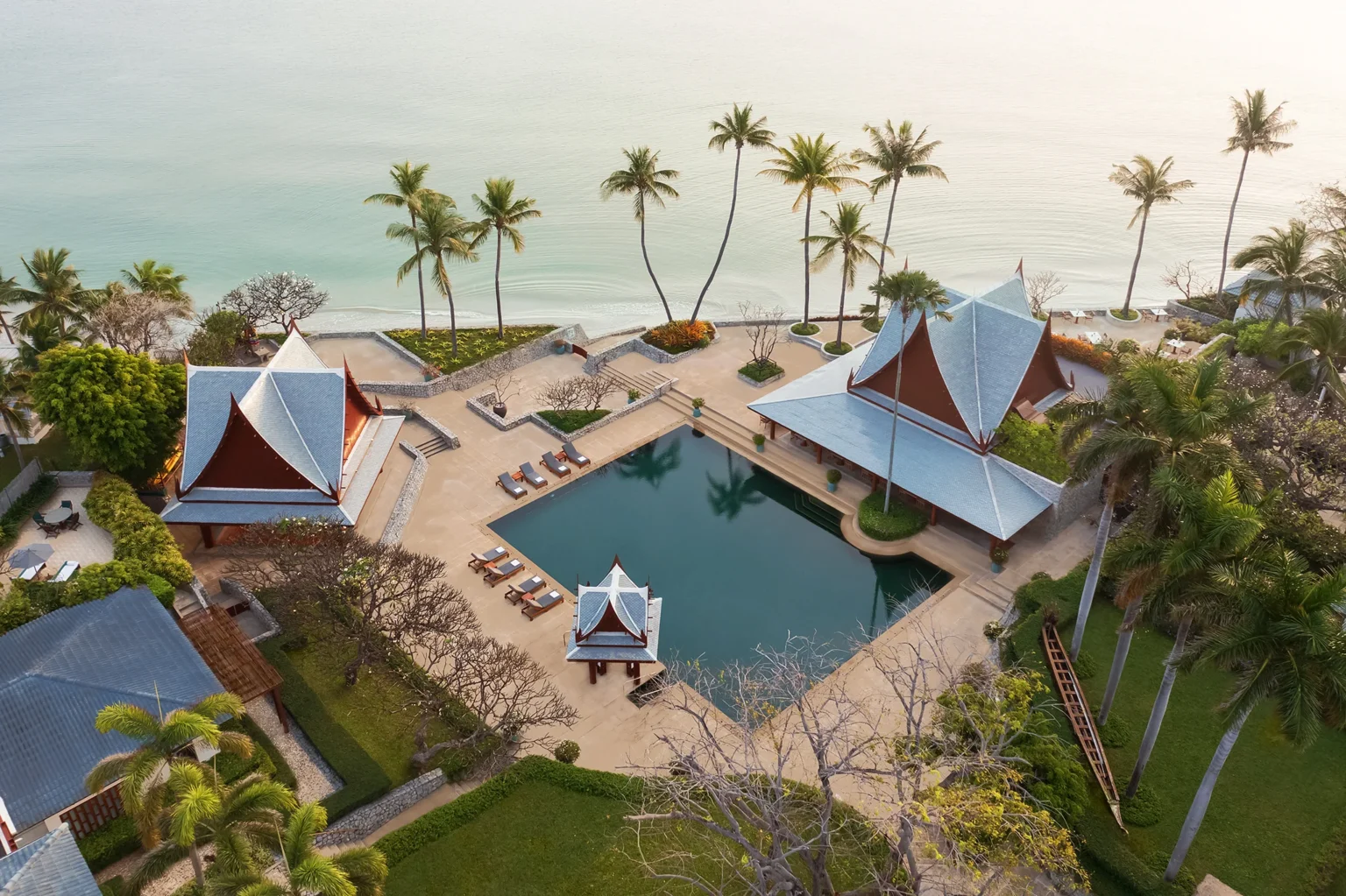 Blick von oben auf den Pool zwischen den Pavillons direkt am Strand