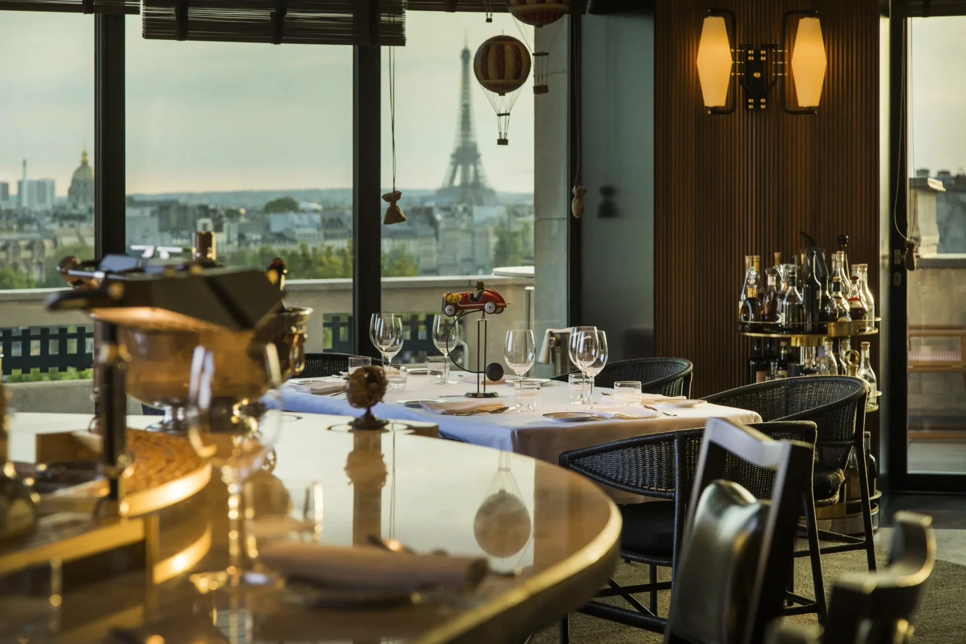 Gedeckter Tisch bei Langosteria mit Blick durch bodentiefe Fenster auf den Eiffelturm im Abendlicht