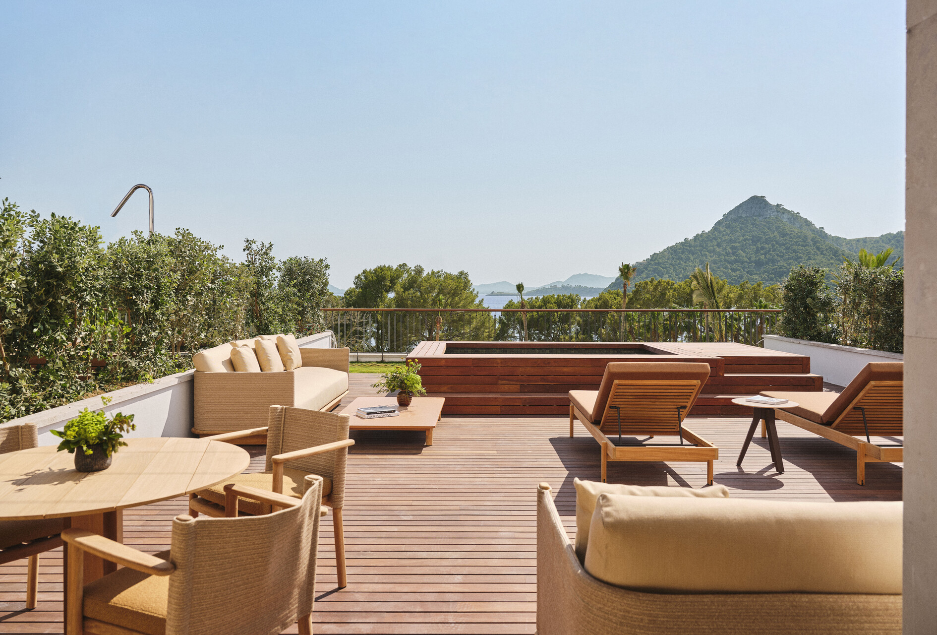 Dachterrasse einer Suite mit Whirlpool, Liegen und Blick auf Bucht und Berge
