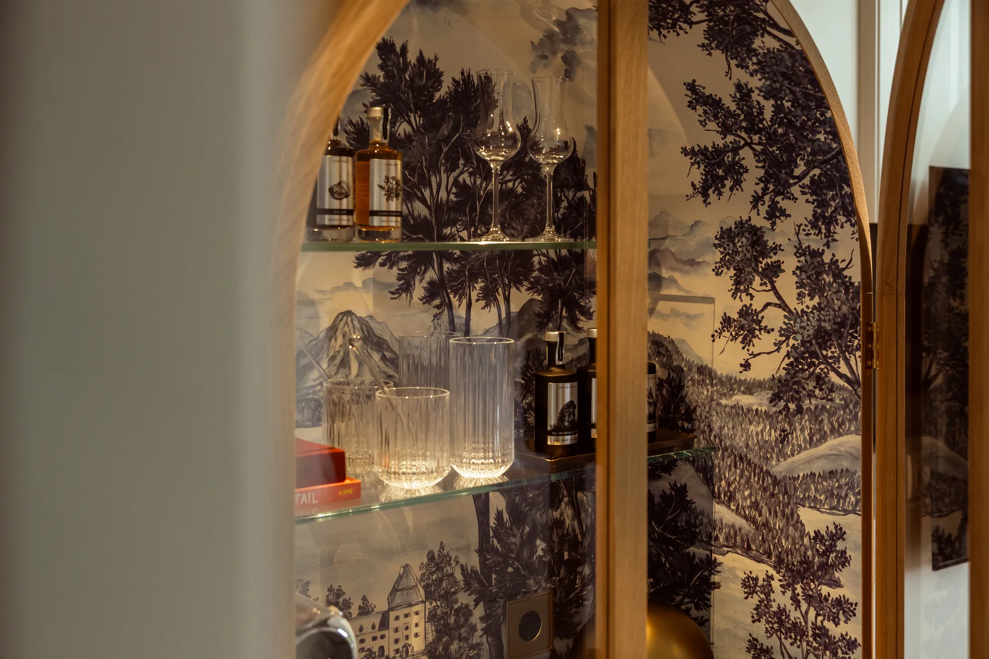 Minibar im Premier Lakeside Room des Rosewood Schloss Fuschl: Bogenschrank mit handgemalter Landschaftstapete, Gläsern und regionalen Spirituosen