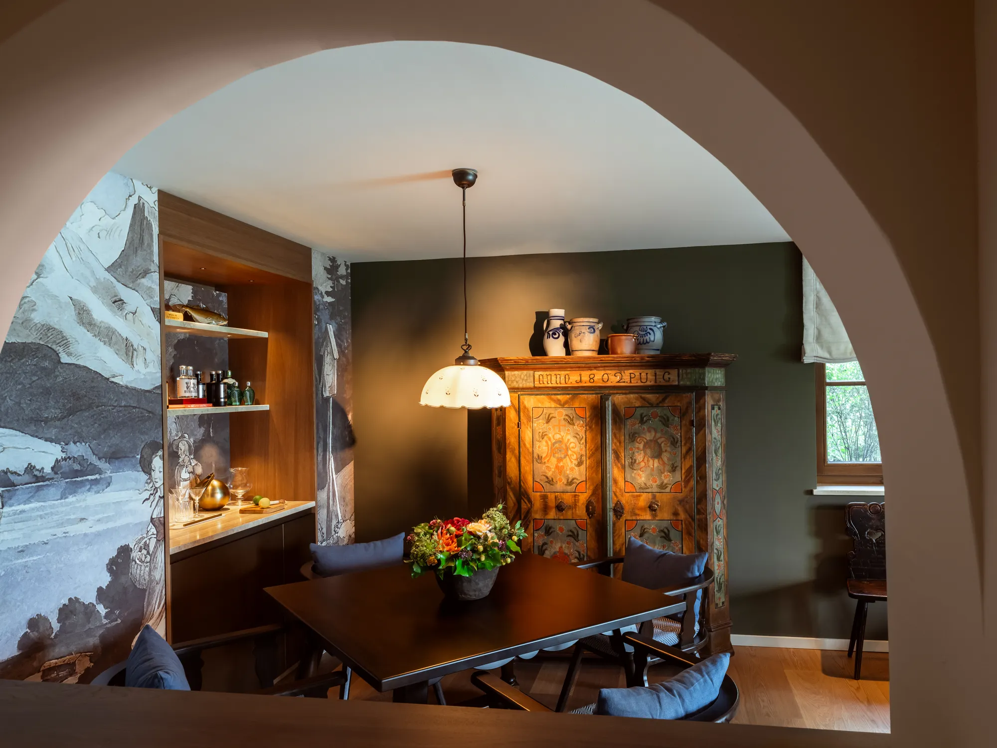 Esszimmer eines Chalets im Rosewood Schloss Fuschl mit Gewölbebogen, bemaltem Bauernschrank von 1802 und Wandmalerei