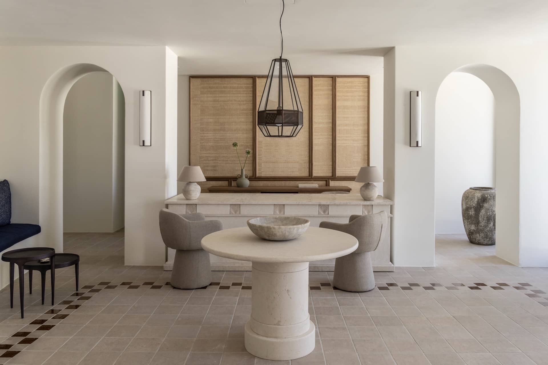 Lobby der Villas at Parīlio mit rundem Steintisch, Bögen, geflochtenen Wandpaneelen und Terrakottaboden