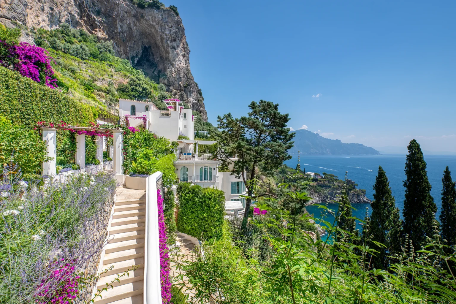 Weisse Terrassen und Treppen des Borgo Santandrea zwischen Bougainvillea und Felswand