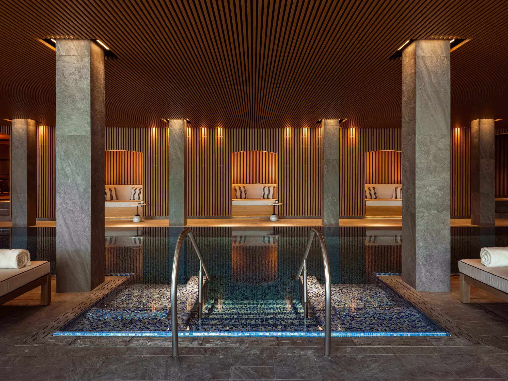 Innenpool des Asaya Spa im Rosewood Schloss Fuschl mit ruhiger Wasserfläche und Fenstern ins Grüne