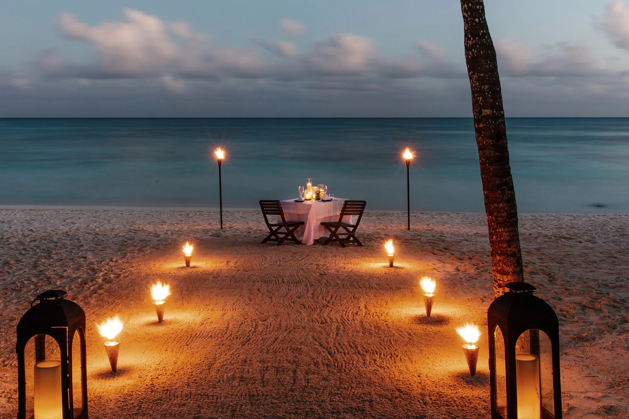 Einzeln gedeckter Tisch mit Kerzen am Strand nach Sonnenuntergang