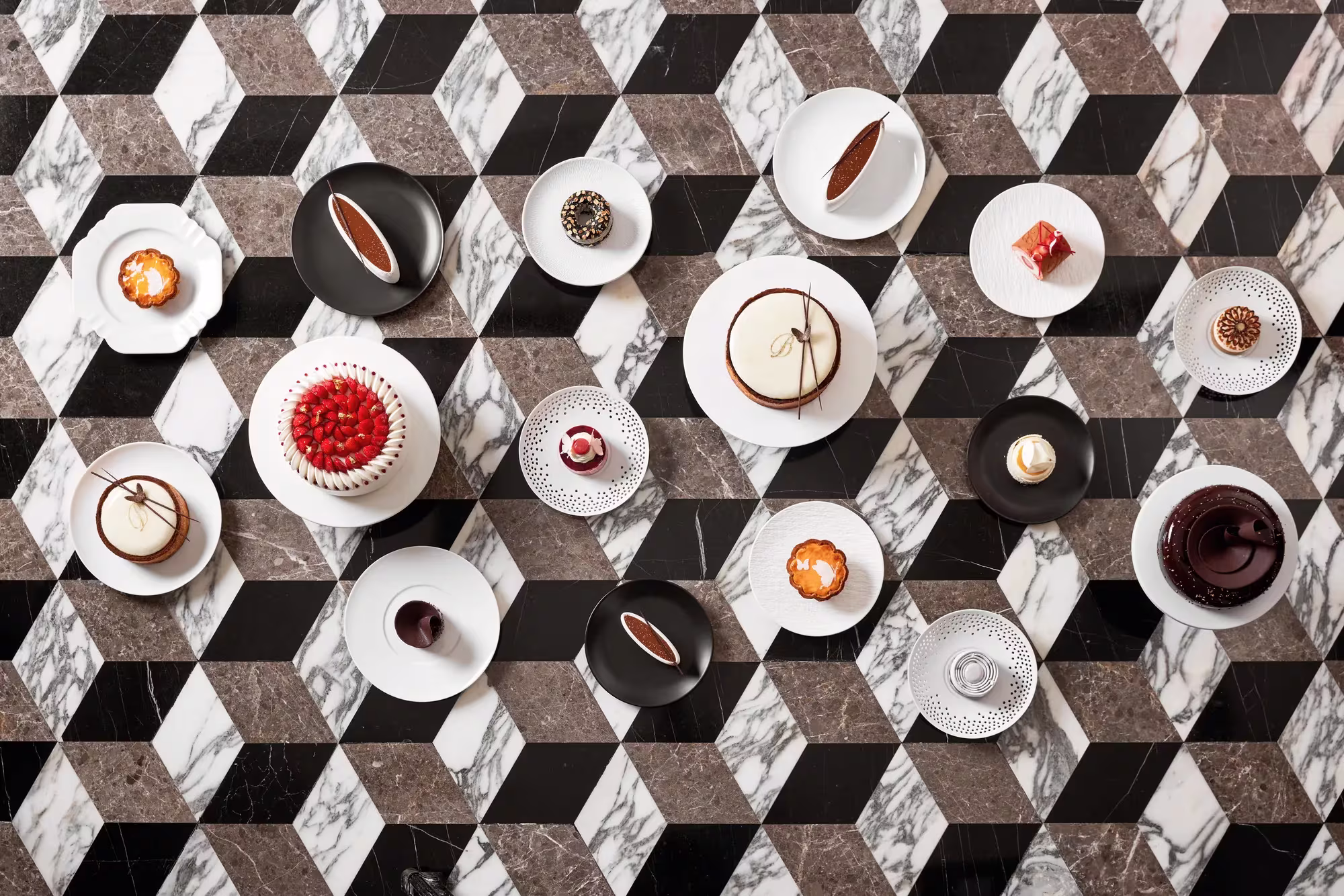 Törtchen und Pralinen der Butterfly Patisserie im Rosewood Hong Kong, sorgfältig auf hellem Stein arrangiert