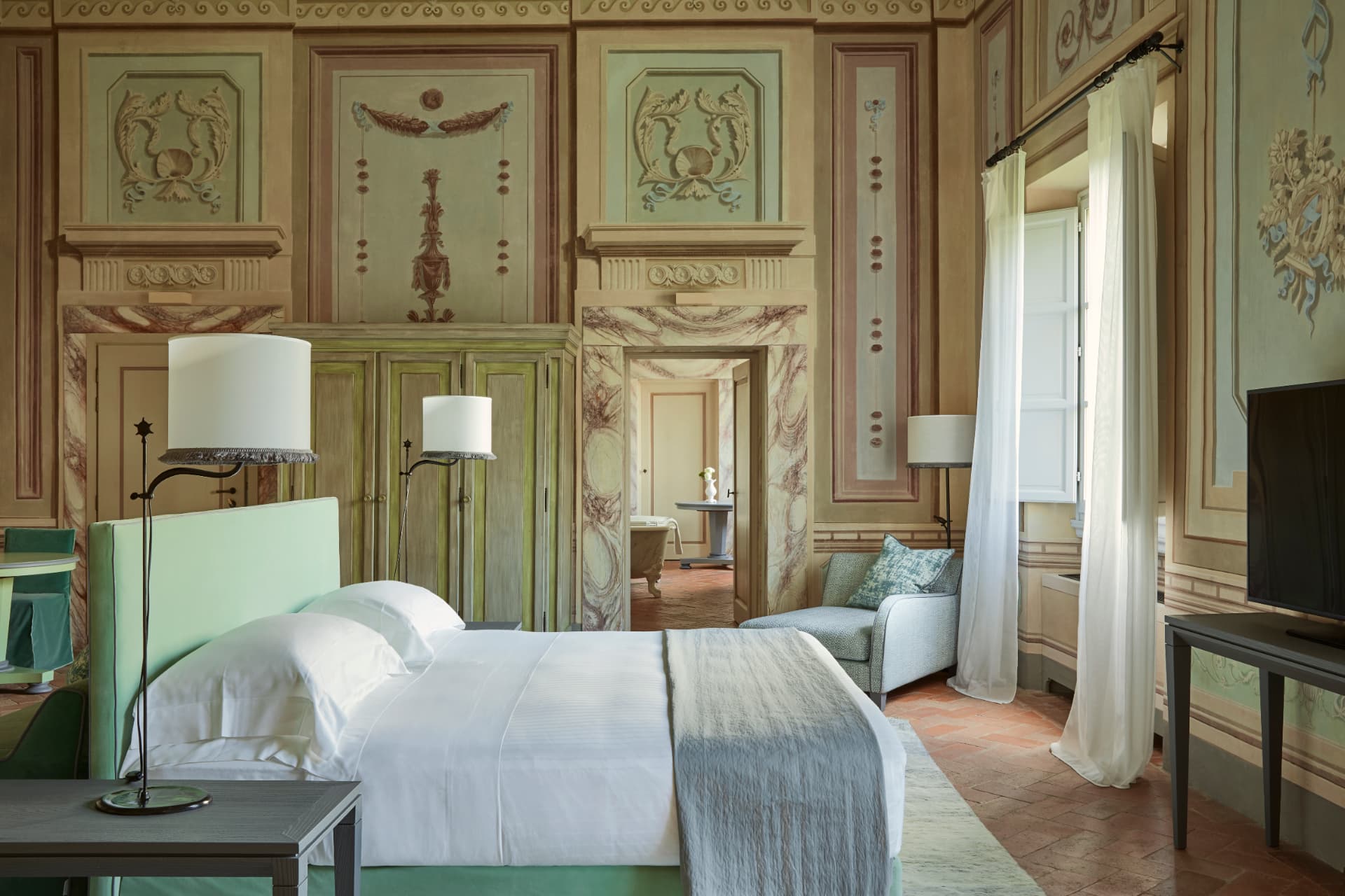 Schlafraum der Heritage Suite mit historischen Wandmalereien, Terrakottaboden und offenem Fenster