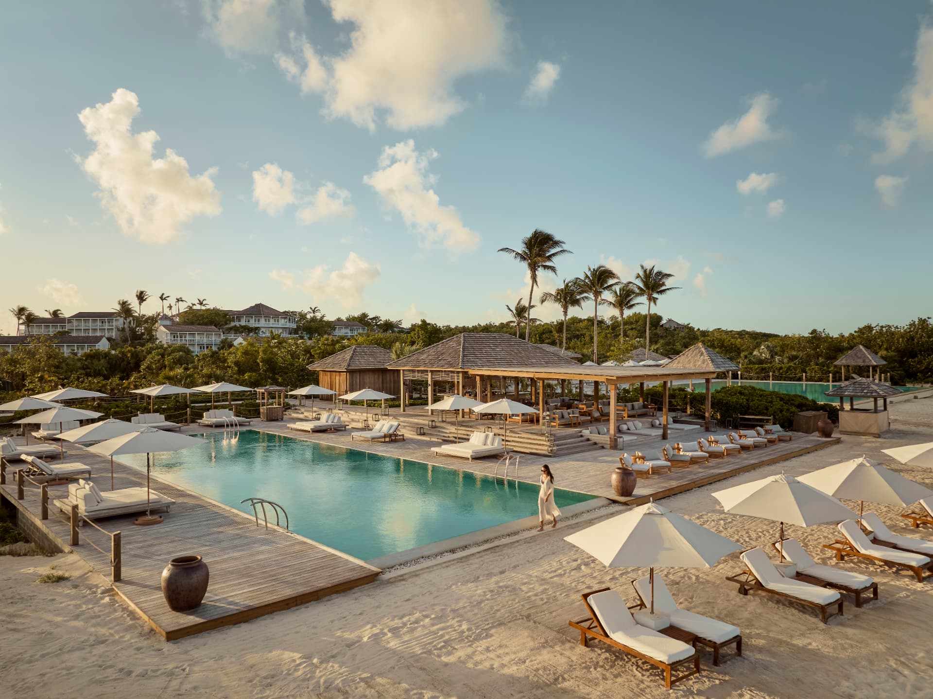 Beach Club für Erwachsene mit langem Pool, Holzdeck und Pavillons im Abendlicht