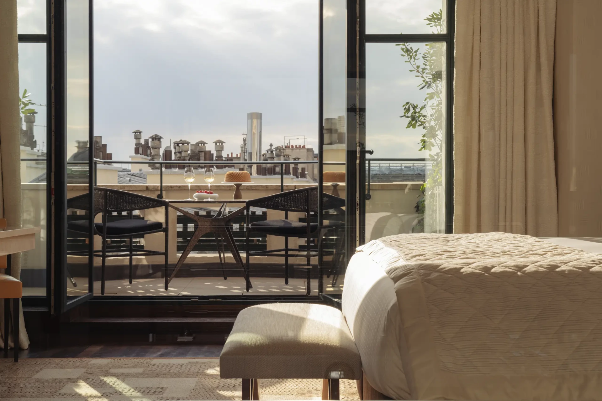 Balkon eines Deluxe Zimmers mit gedecktem Tisch über den Dächern und Kaminen von Paris