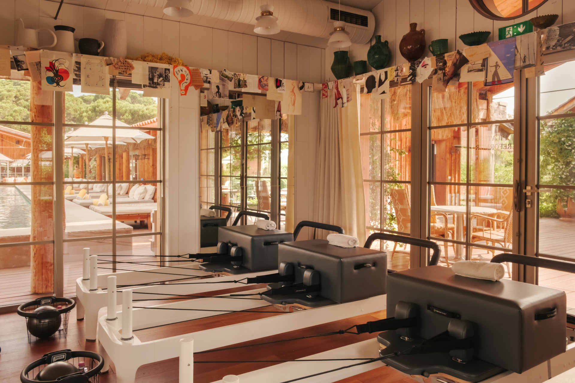 Pilates-Studio mit Reformern, Holzboden und Blick auf den Pool
