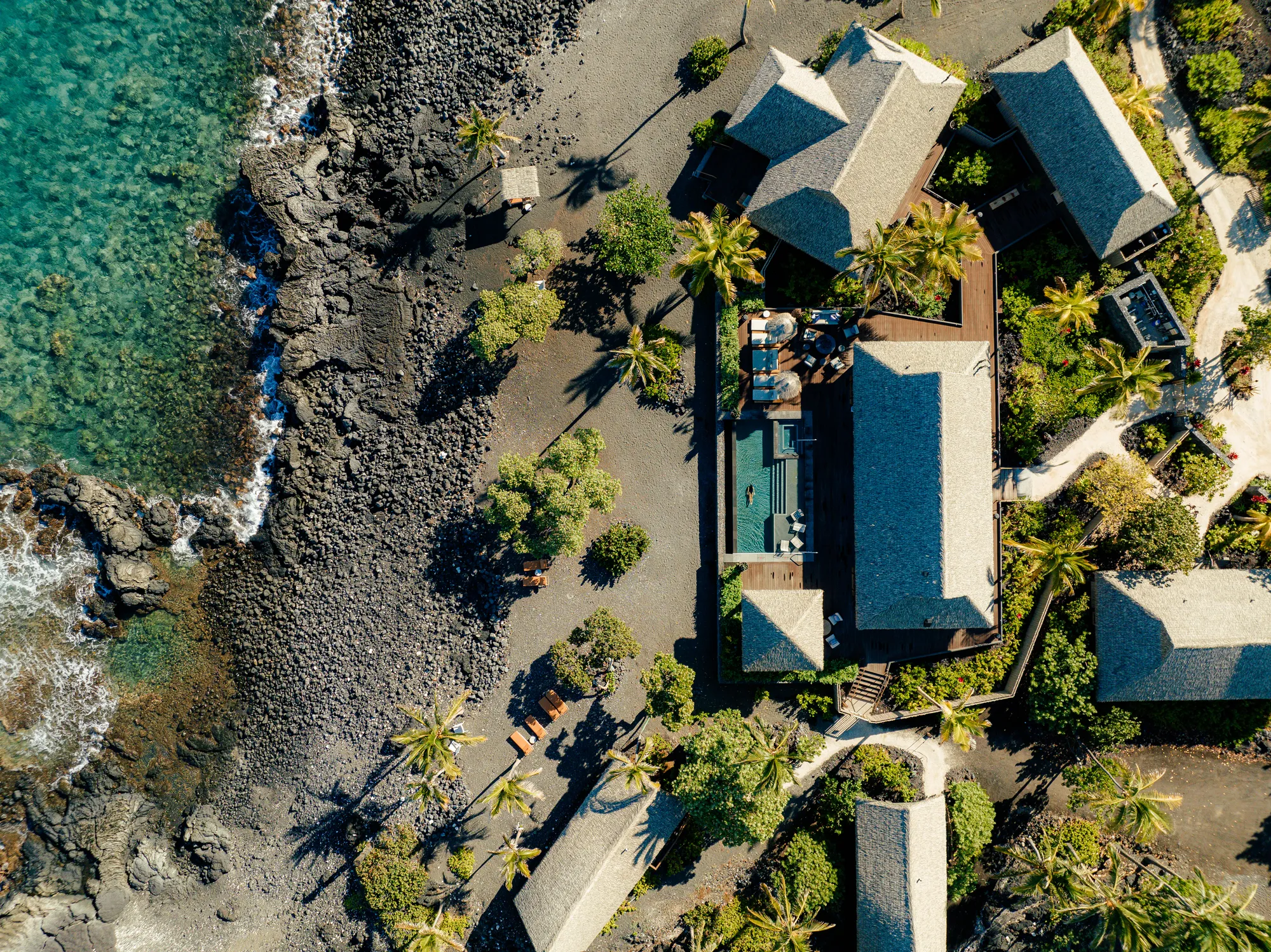 Senkrechte Luftaufnahme einzelner Hale des Rosewood Kona Village am schwarzen Lavastrand