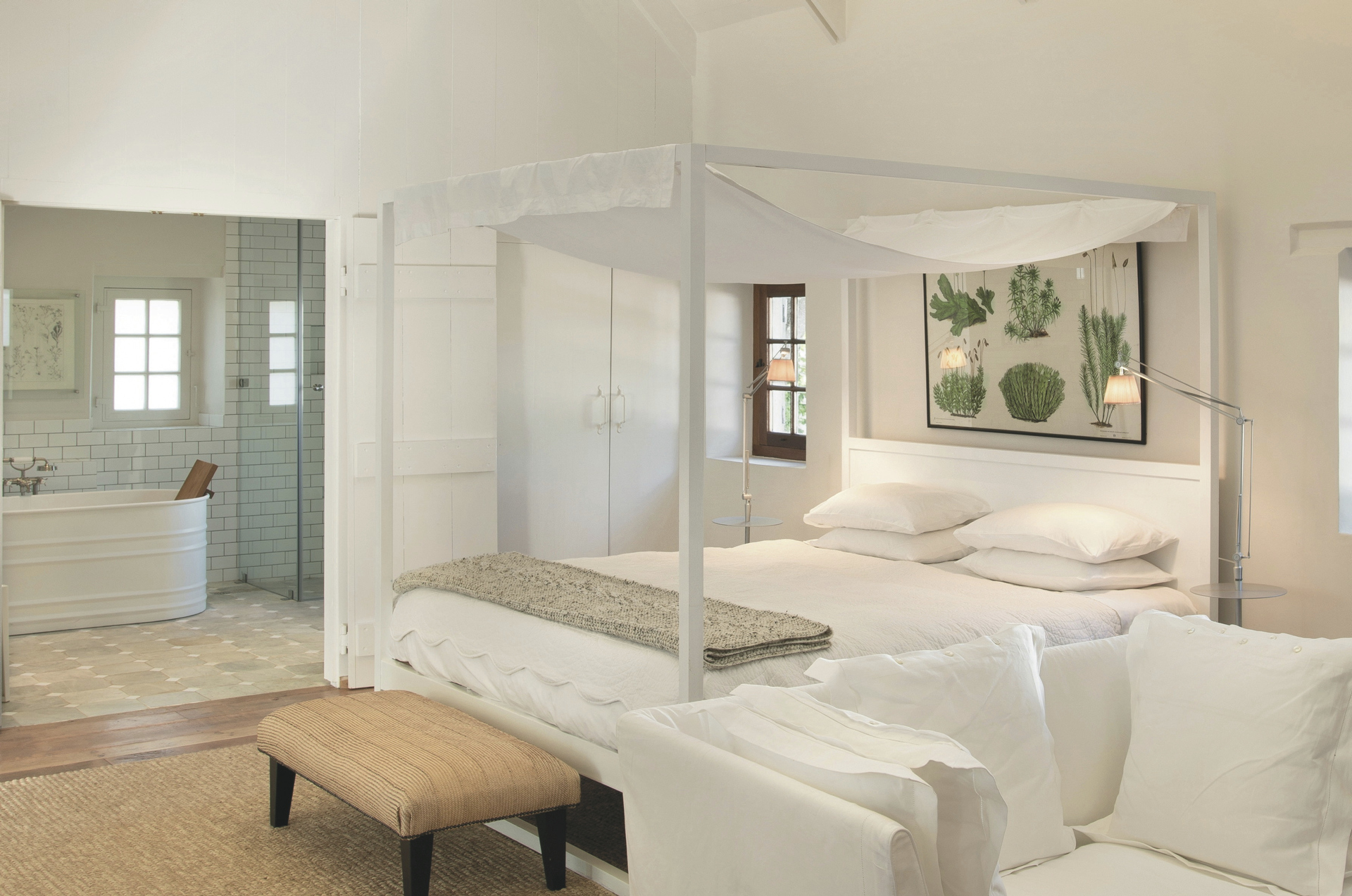 Schlafraum eines Cottage mit weissem Himmelbett und offenem Bad