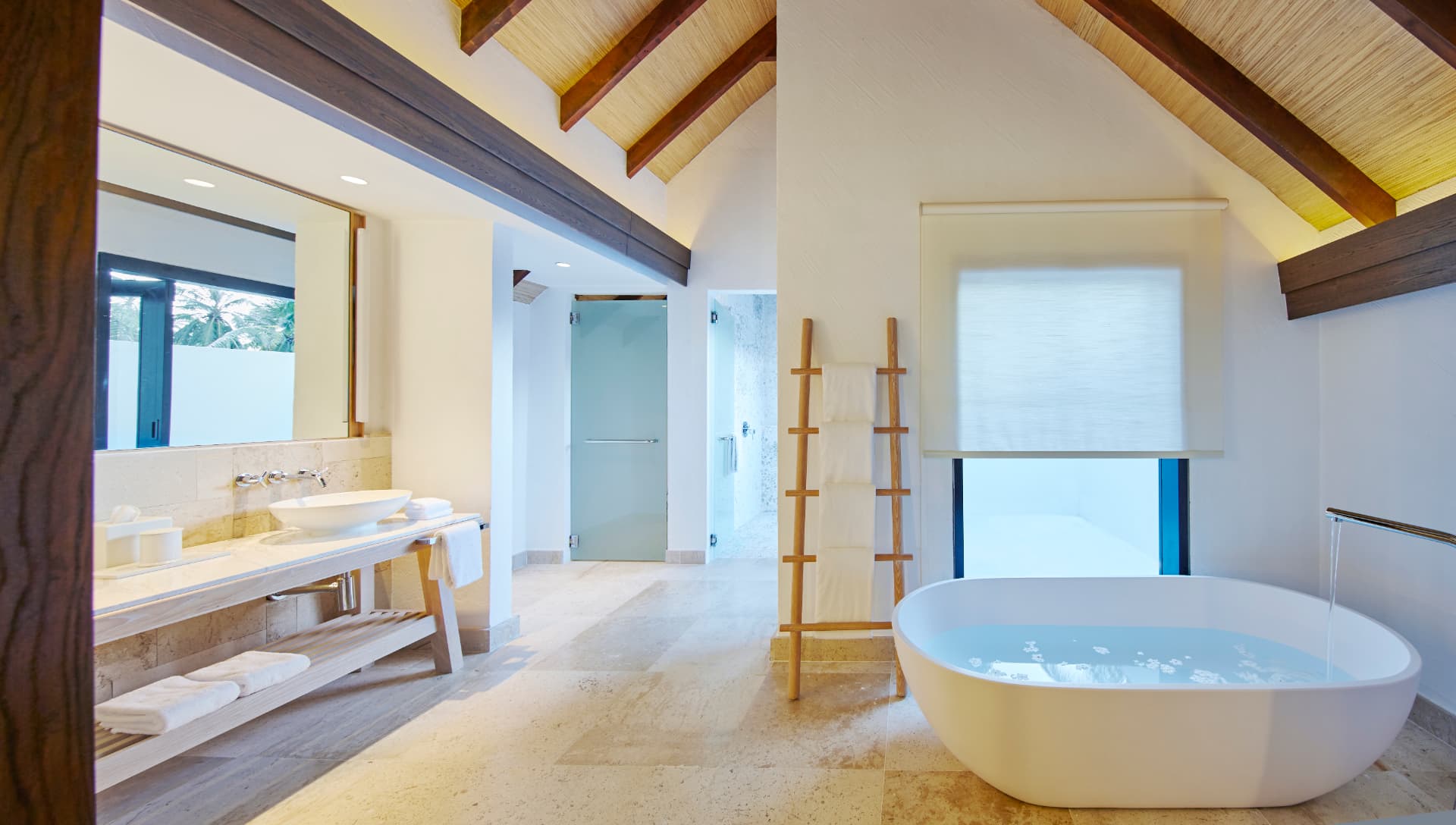 Bad der Wasservilla mit freistehender Wanne unter hohem Holzdach